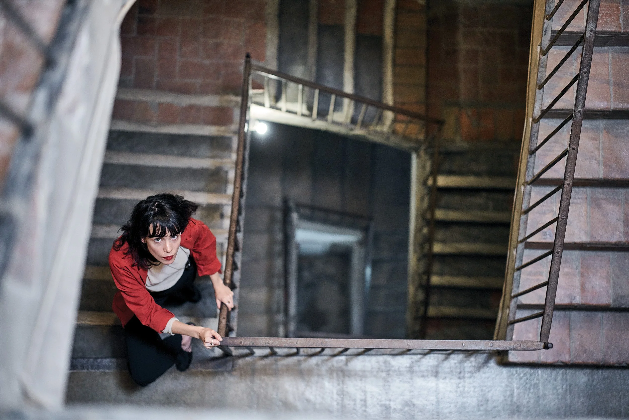 looking down a spiral staircase at blanca micro sitting on a step
