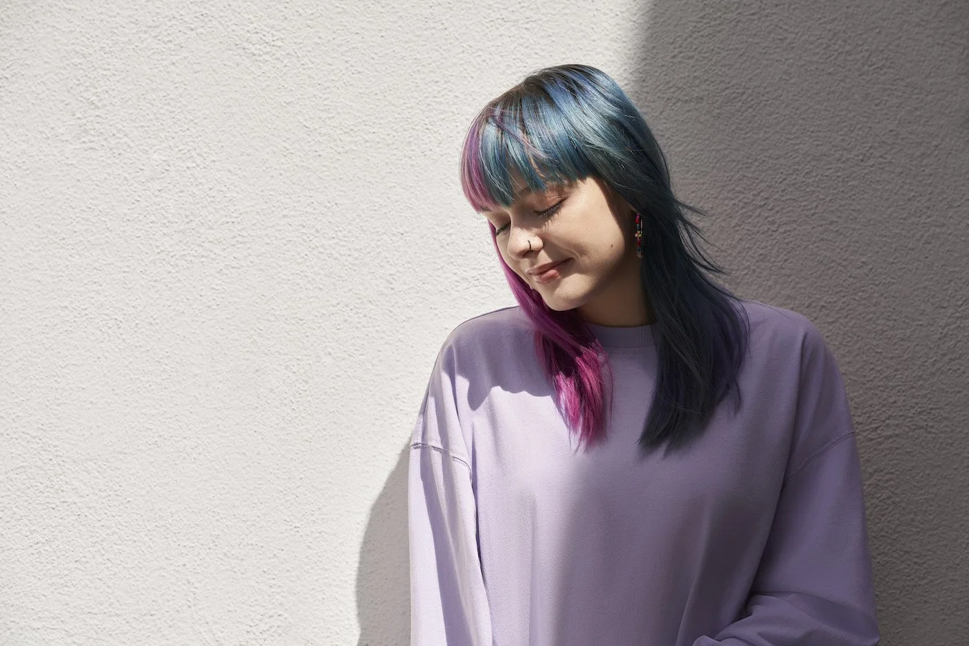 woman with pink and purple hair smiling and looking down