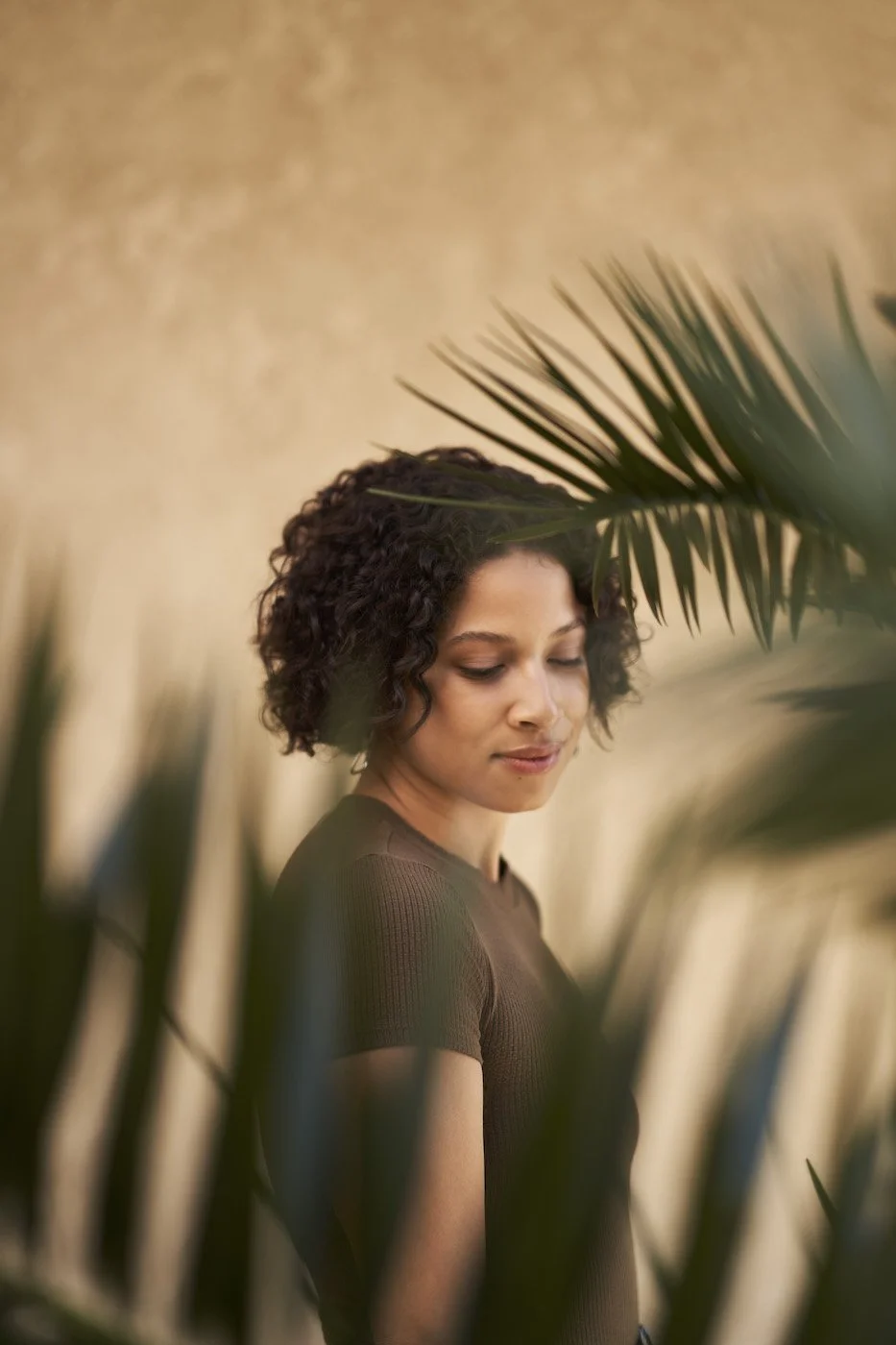 woman standing between palm tree fronds