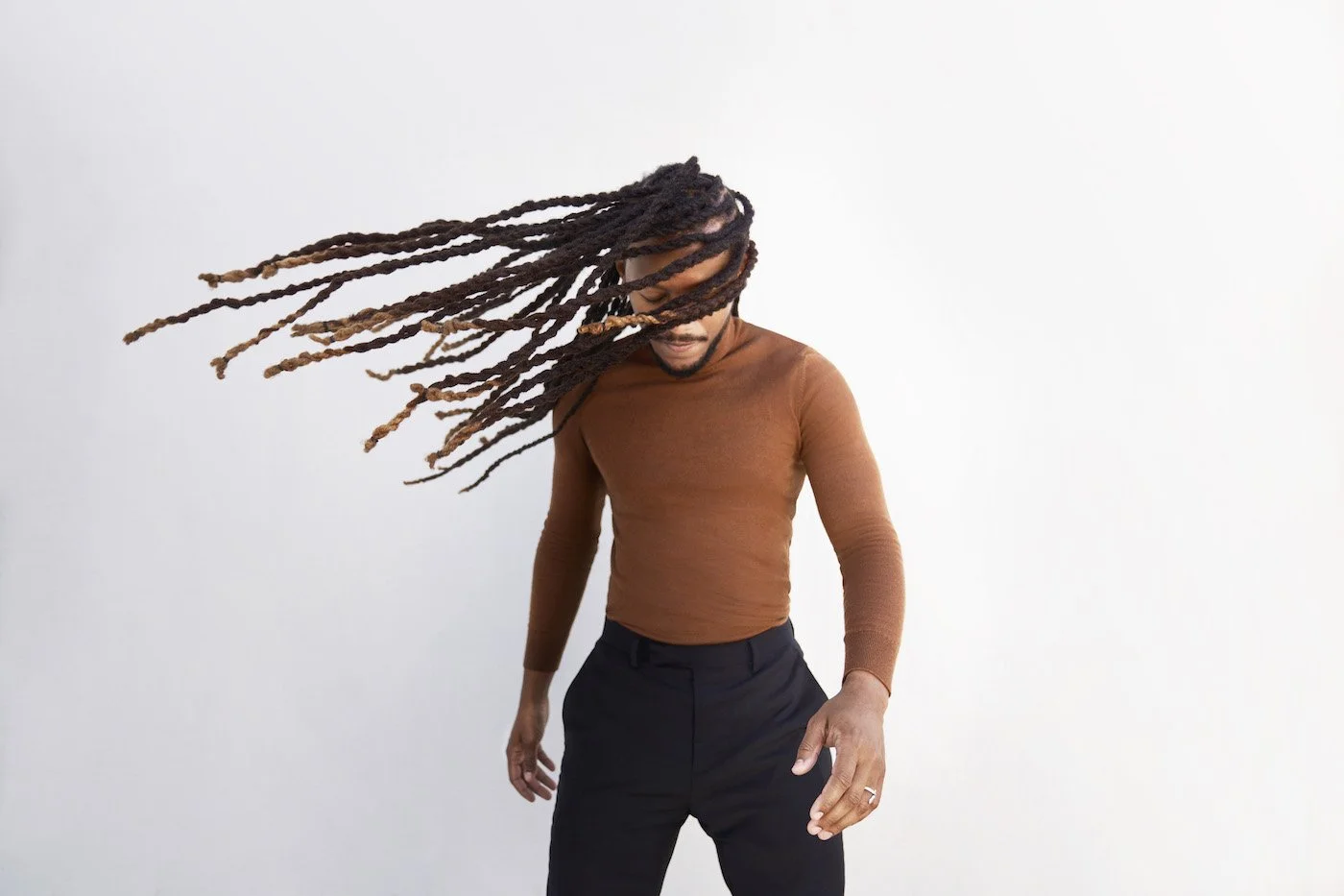 man in brown sweater with long hair blowing in the wind