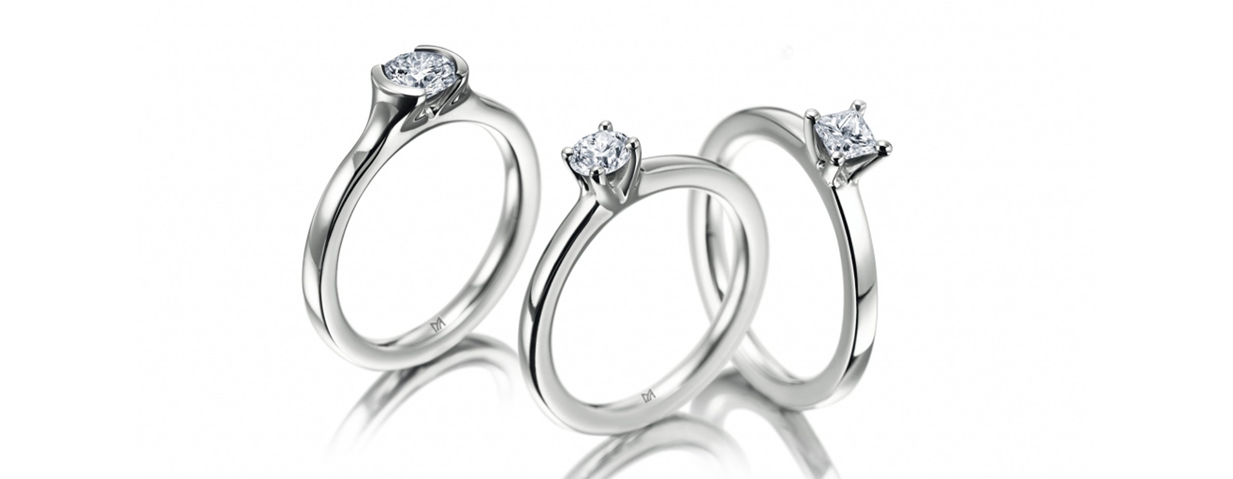 Drei elegante Weißgoldringe mit Diamanten auf weißem Hintergrund