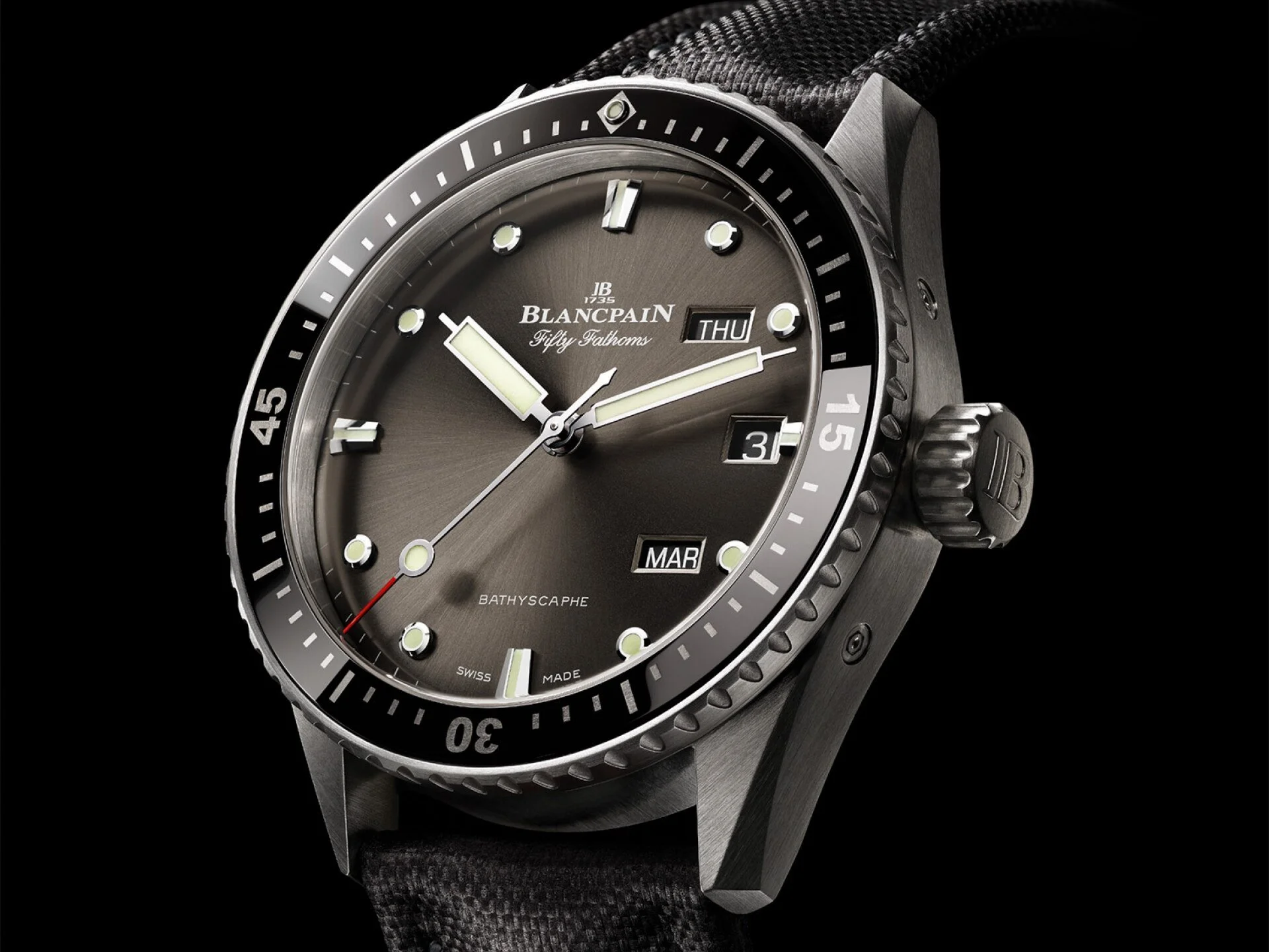 Nahaufnahme einer Blancpain Fifty Fathoms Bathyscaphe Taucheruhr mit schwarzer Lünette, grauem Zifferblatt und Textilarmband
