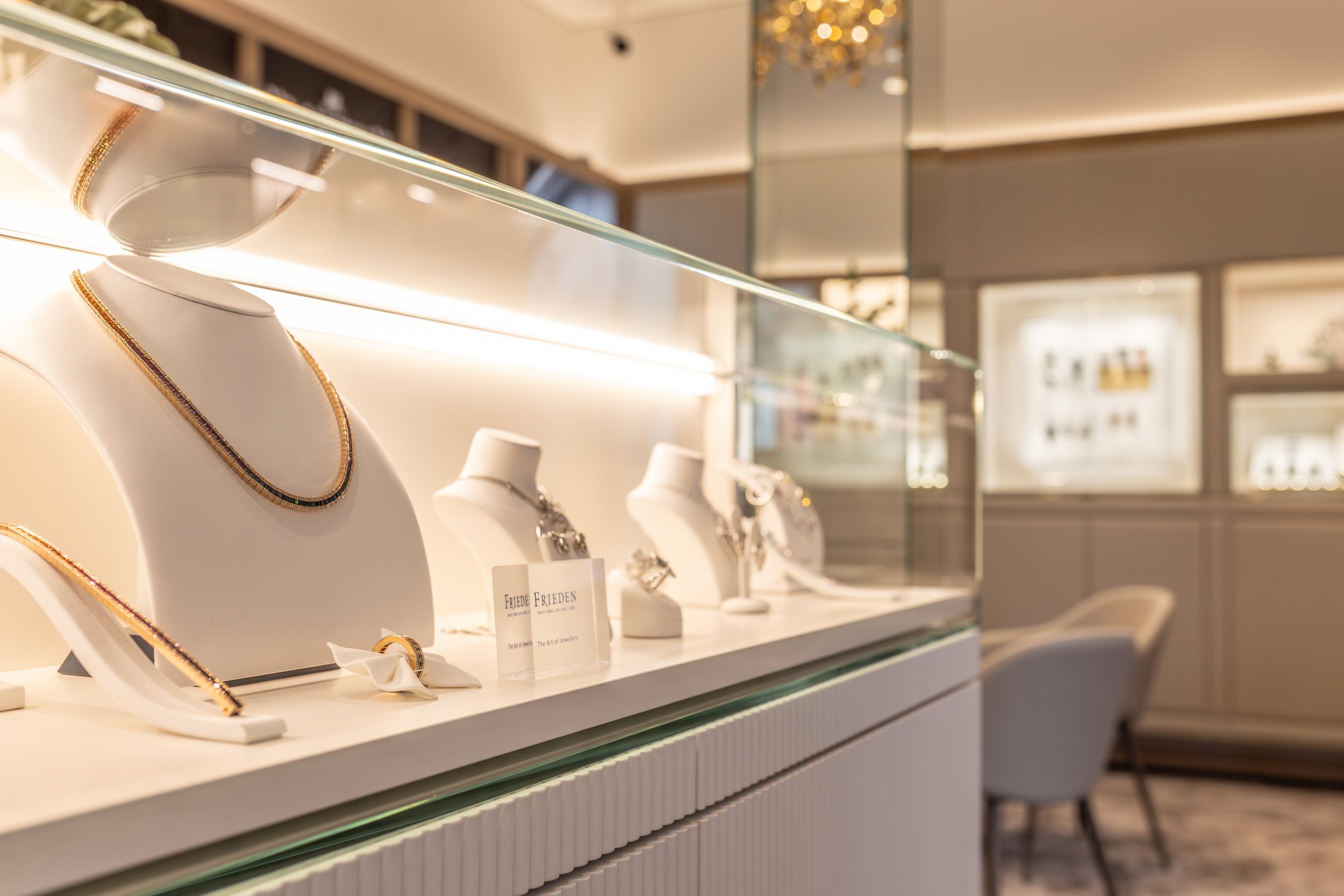 Elegante Schmuckvitrine mit ausgestellten Halsketten, Ringen und Schmuckbüsten in einem Juweliergeschäft.