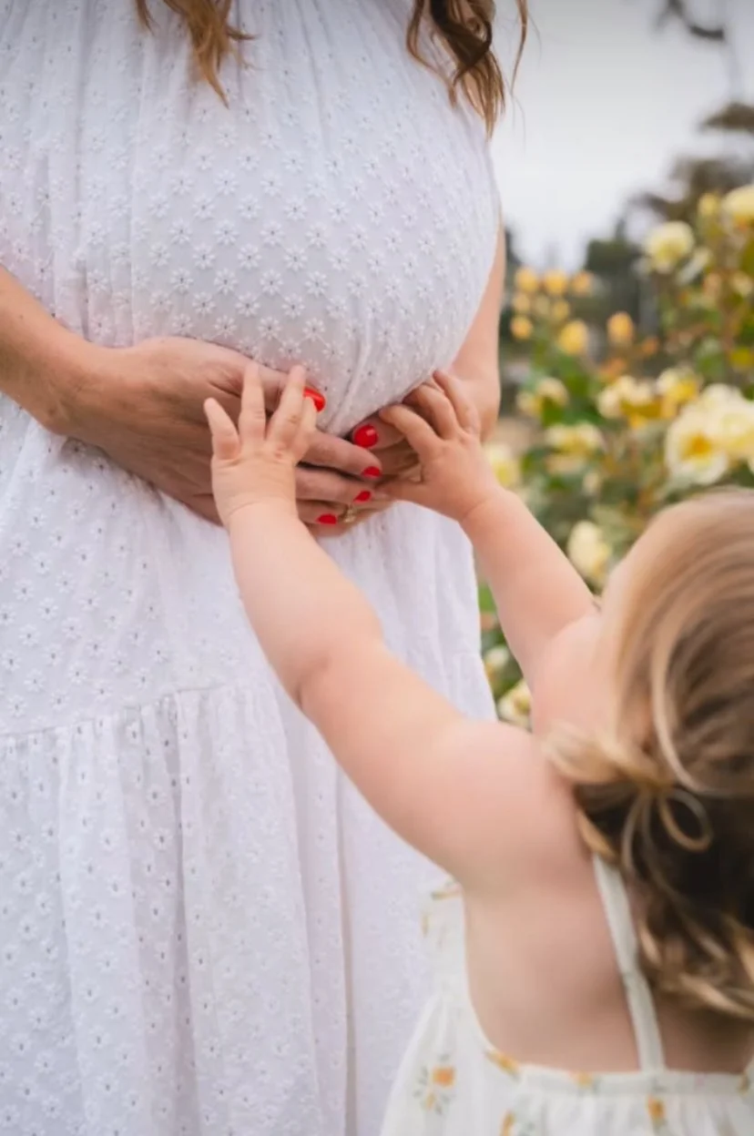 Child touching pregnant mother's belly
