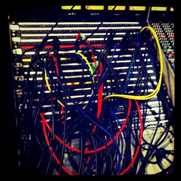 A patch panel with multiple colored Ethernet cables connected, including black, red, yellow, and green, in a network setup or data center.