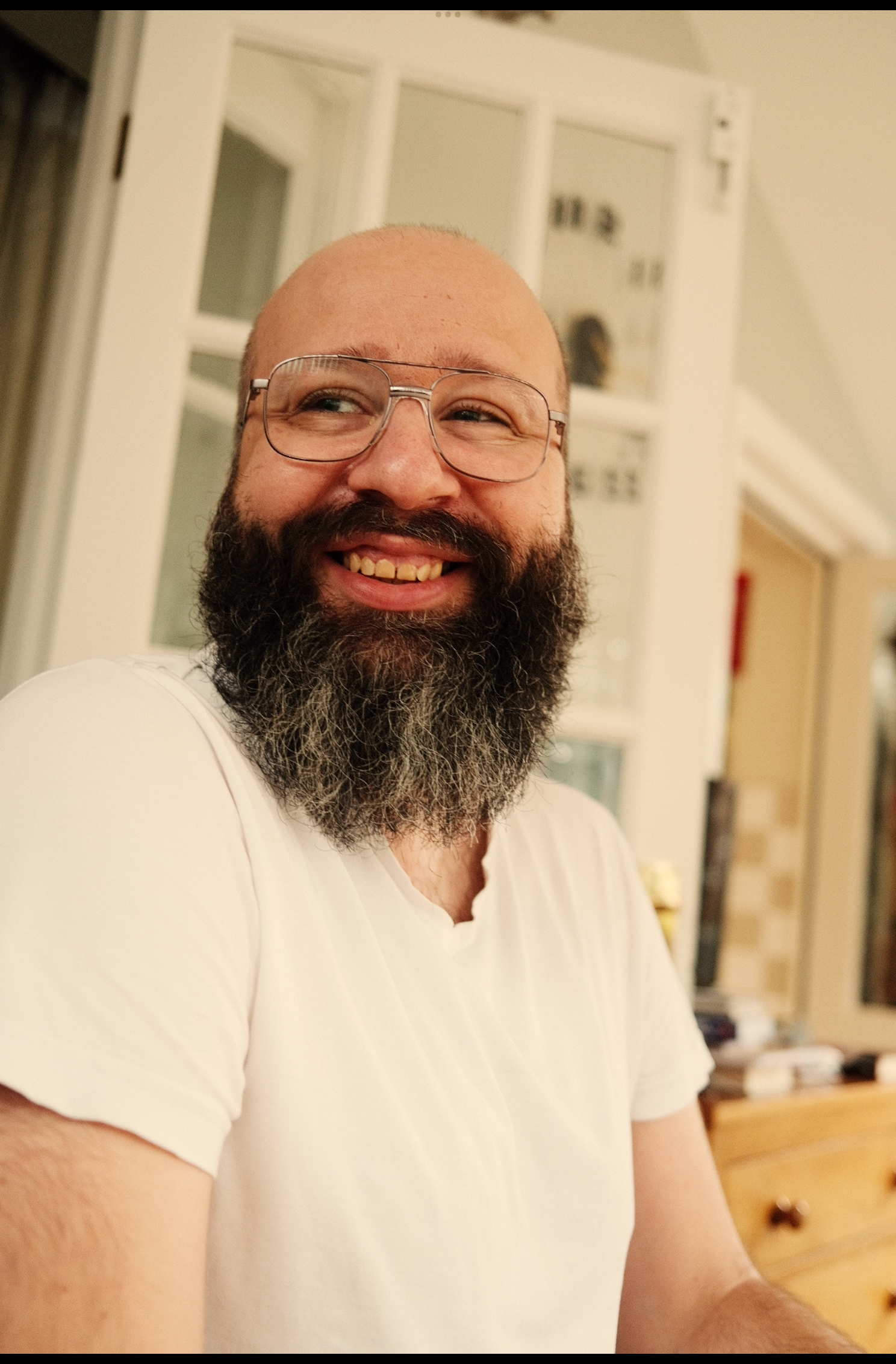 A smiling bearded man with glasses.