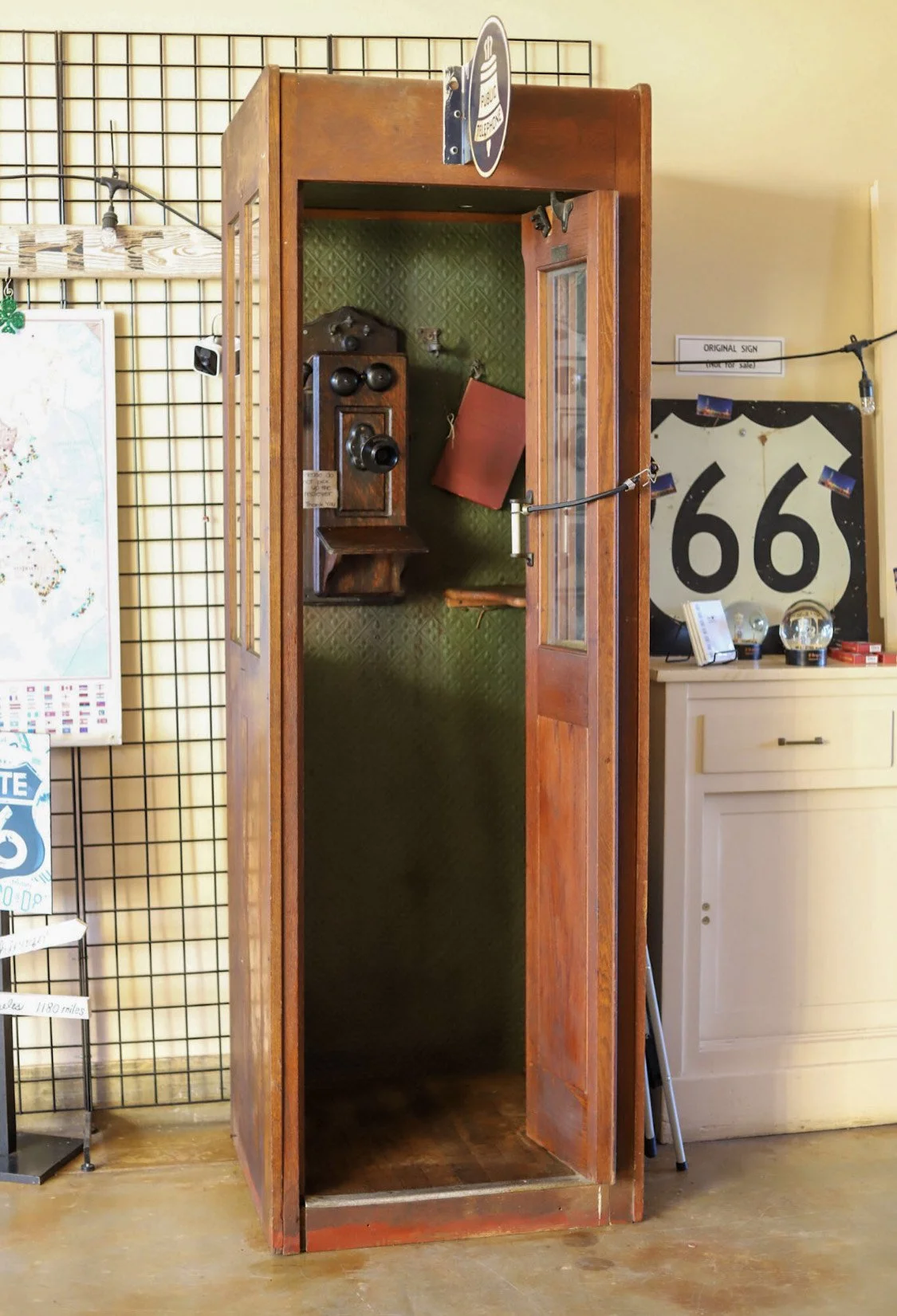 Vintage wooden telephone booth with an old-fashioned wall-mounted telephone inside.