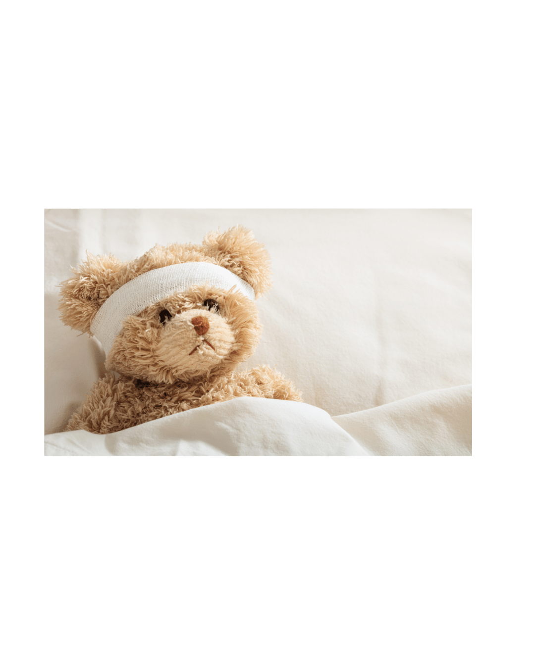 A plush teddy bear with a bandage on its head, sitting on a white surface, looking sad.
