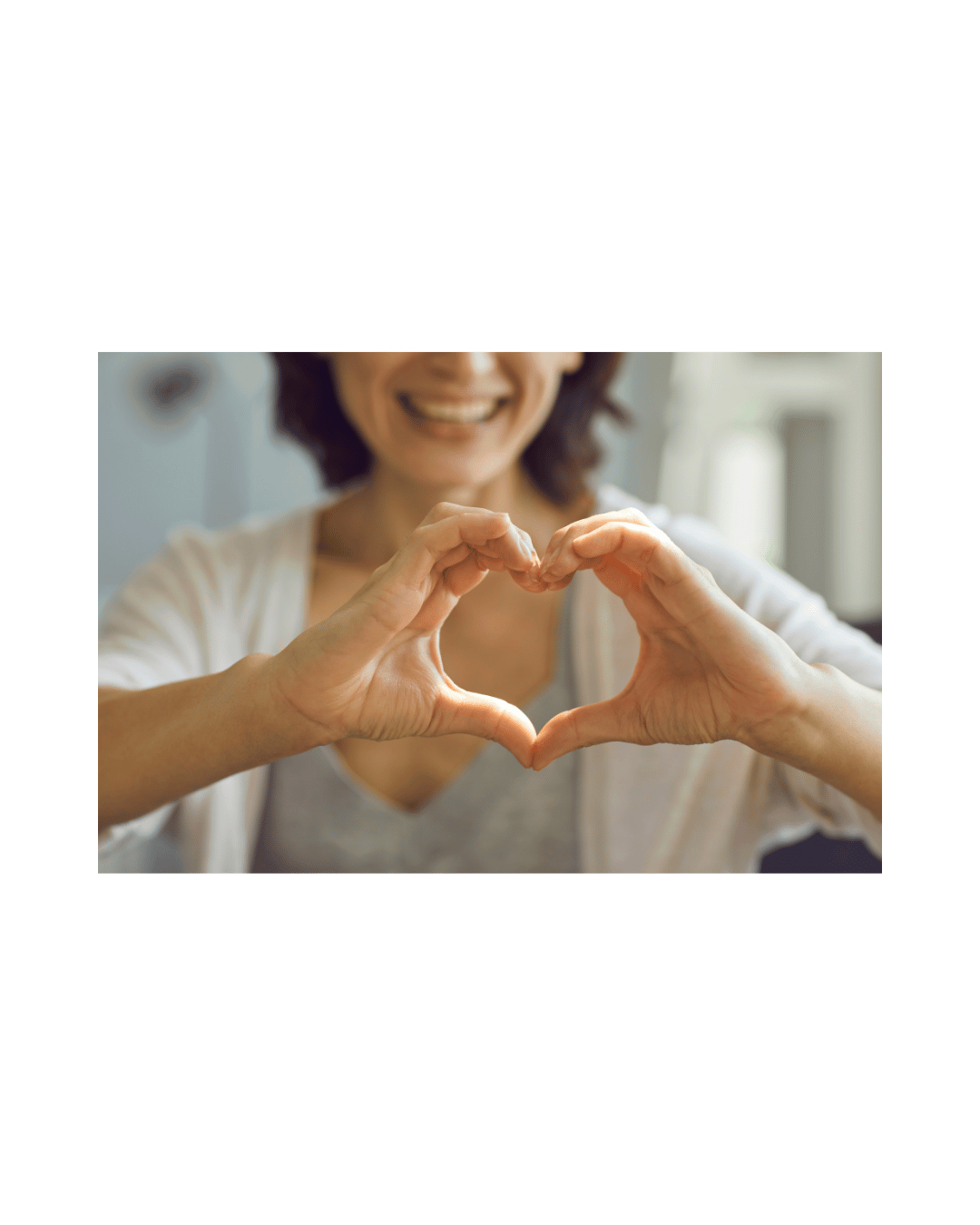 Woman smiling and making a heart shape with her hands.