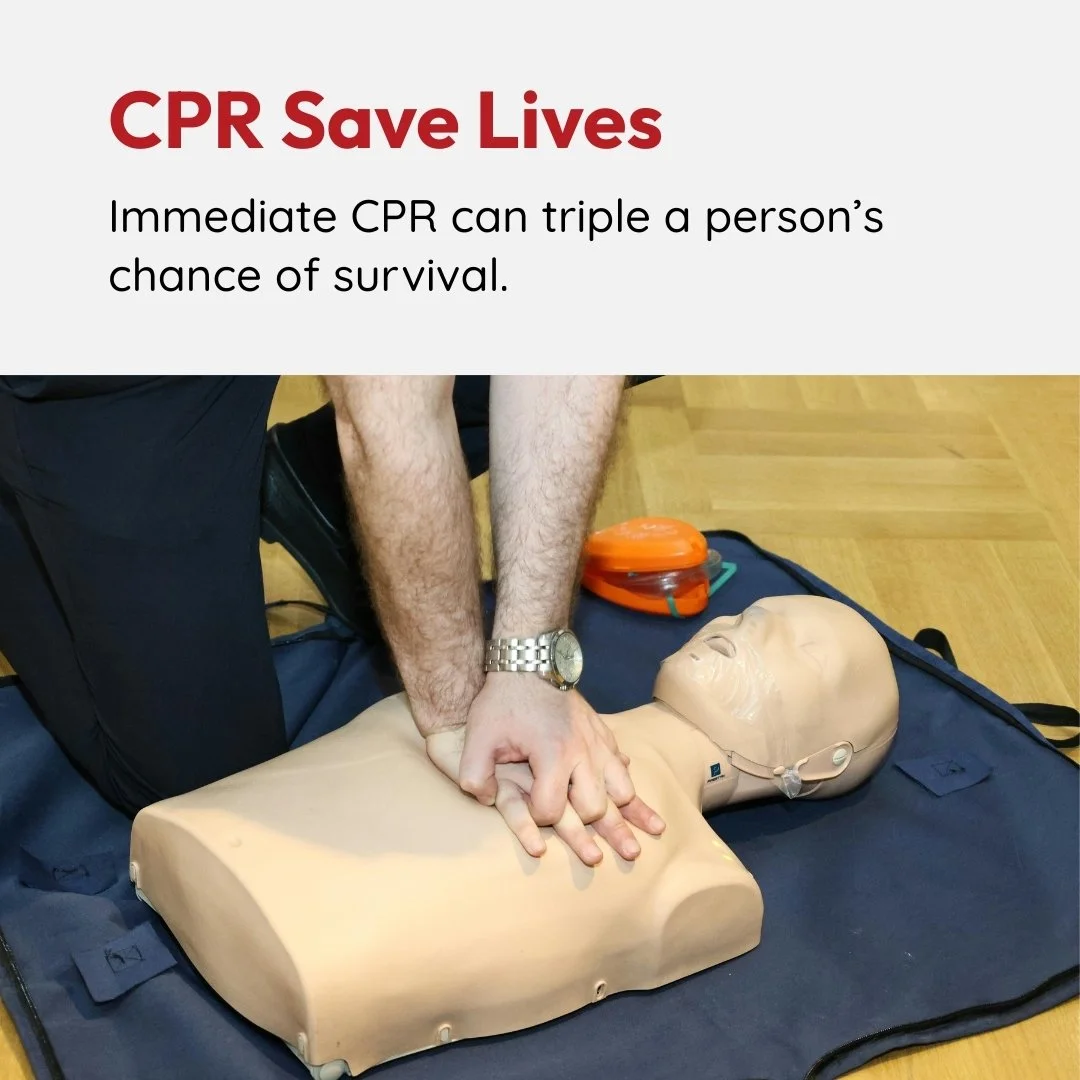 Person performing CPR on a training mannequin on a black mat, with a training AED device nearby, demonstrating life-saving technique.