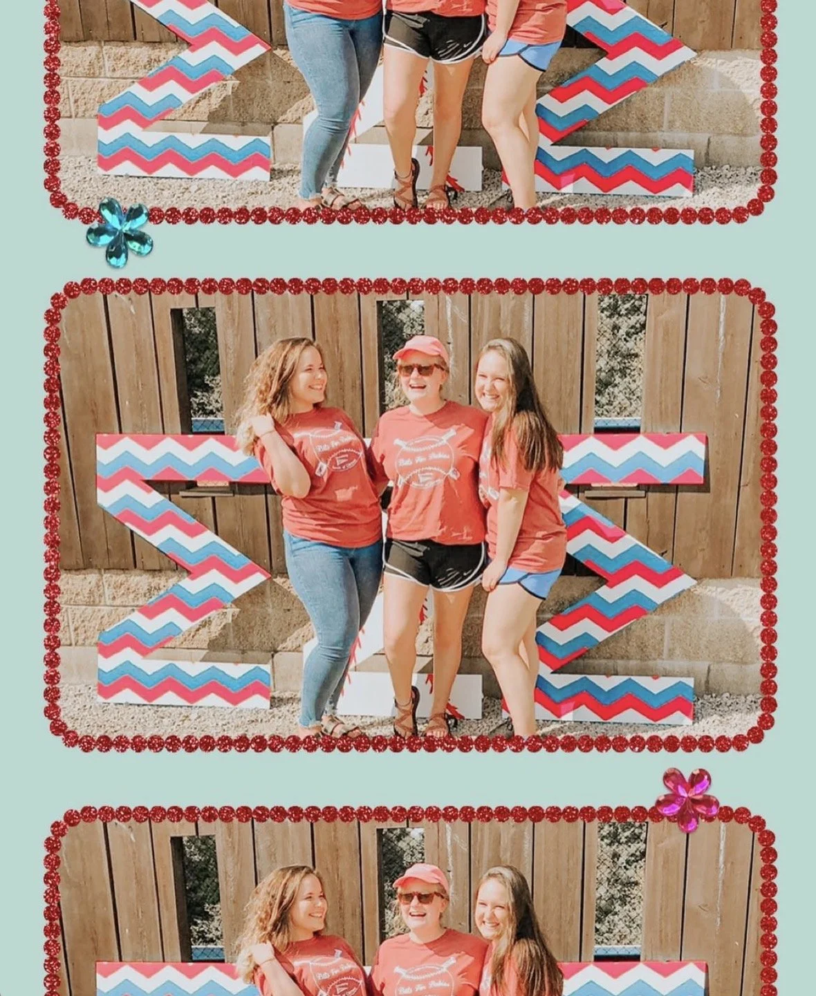 Three women wearing red shirts and black shorts standing outdoors in front of a wooden fence with large decorative red, white, and blue chevron arrows, celebrating together.
