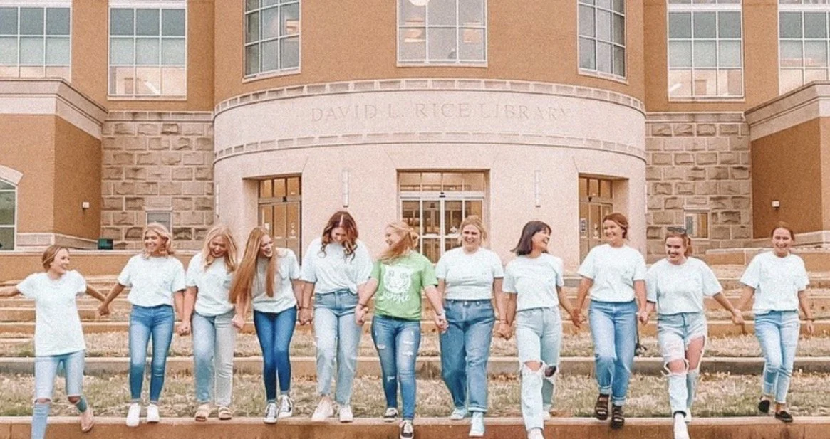 Group of girls holding hands and walking in front of a large brick building labeled 'David L. Rice University'