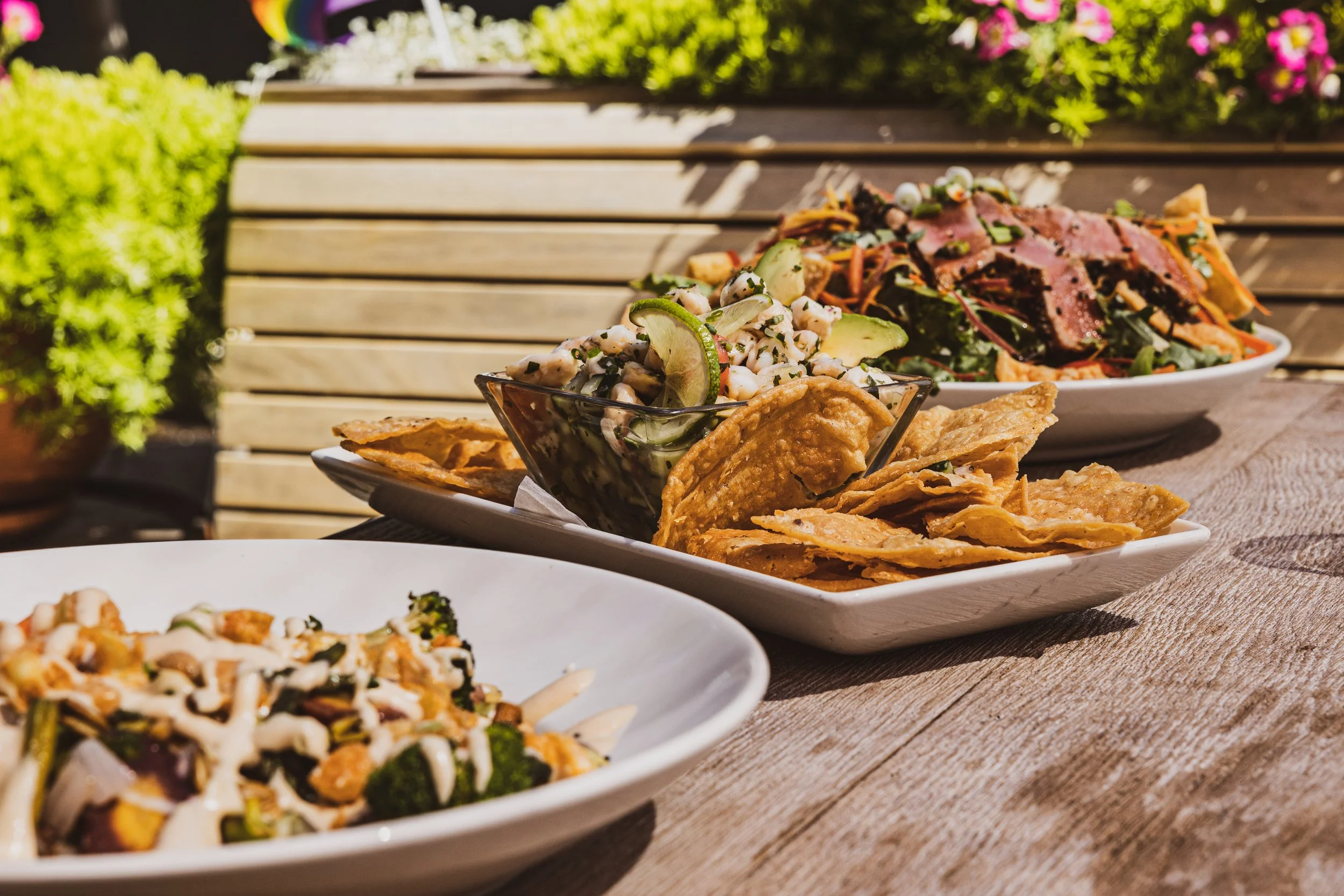 Leeds Public House outdoor patio dining with bowls of salad and tortilla chips, surrounded by greenery