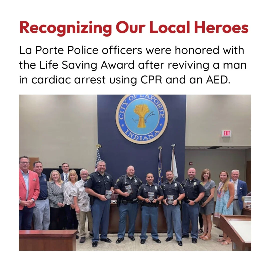 Group photo of La Porte Police officers and community members inside a city hall, honoring officers with a Life Saving Award, with a large city seal in the background.