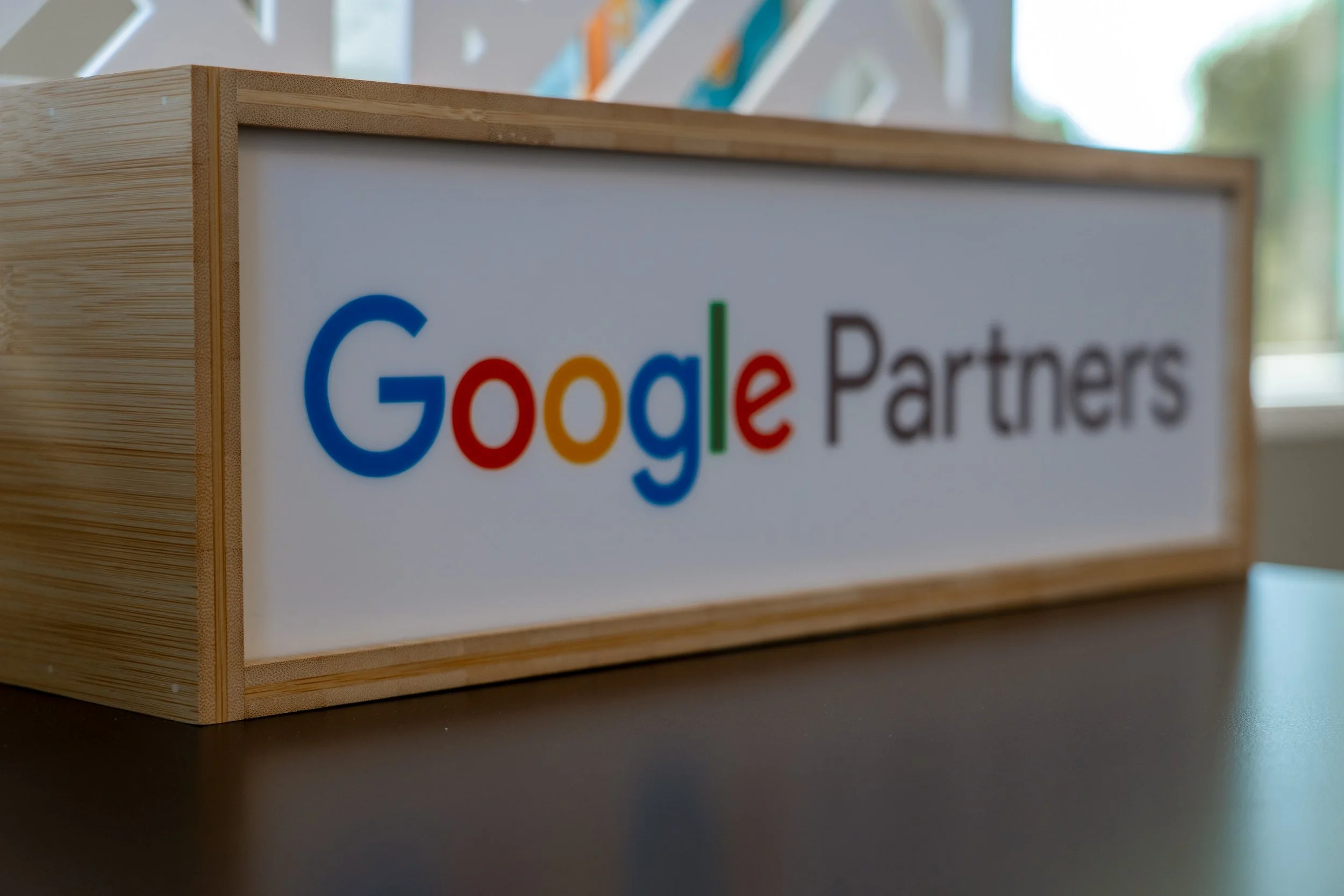 A wooden sign with the Google Partners logo on a white background placed on a table.