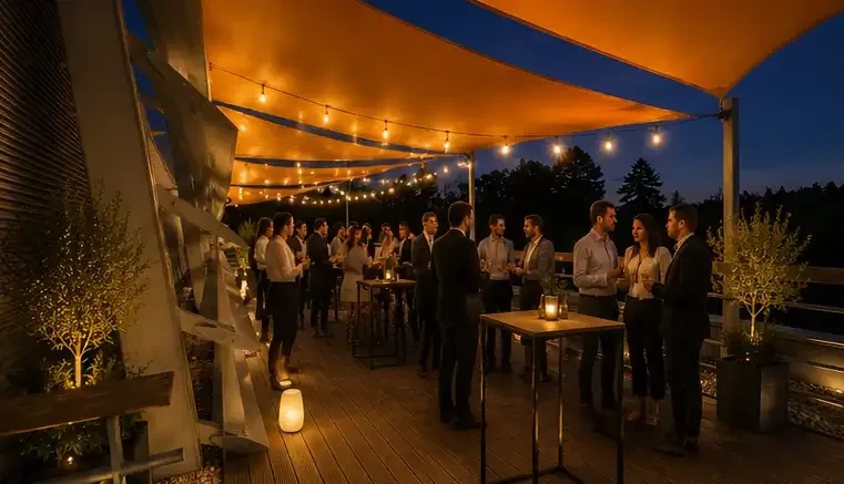 Un rassemblement de personnes lors d'une fête en extérieur le soir, avec des éclairages suspendus et une ambiance chaleureuse.