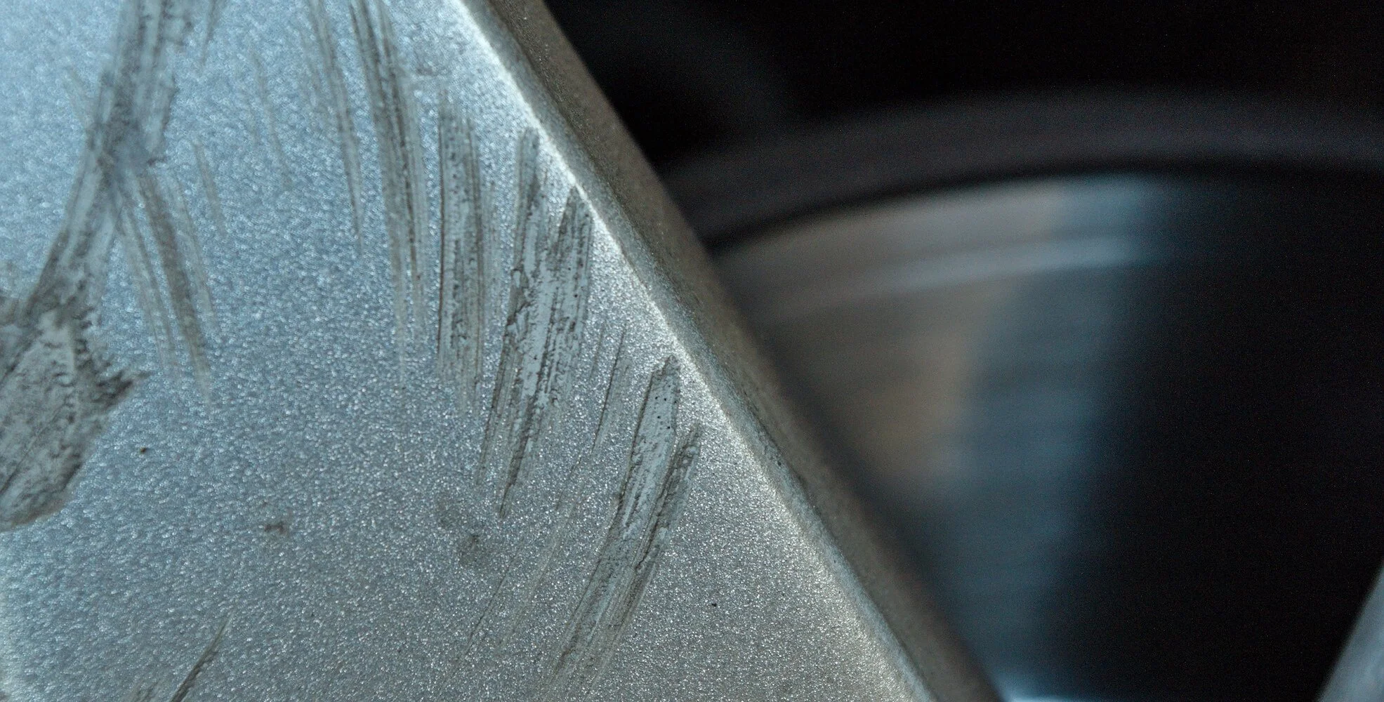 Close-up of a metallic surface with scratches and a textured finish.