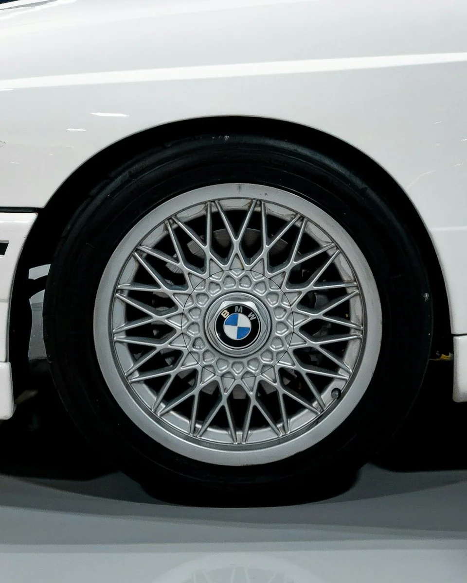 Close-up of a white BMW car wheel with a wire-spoke design and BMW logo in the center.