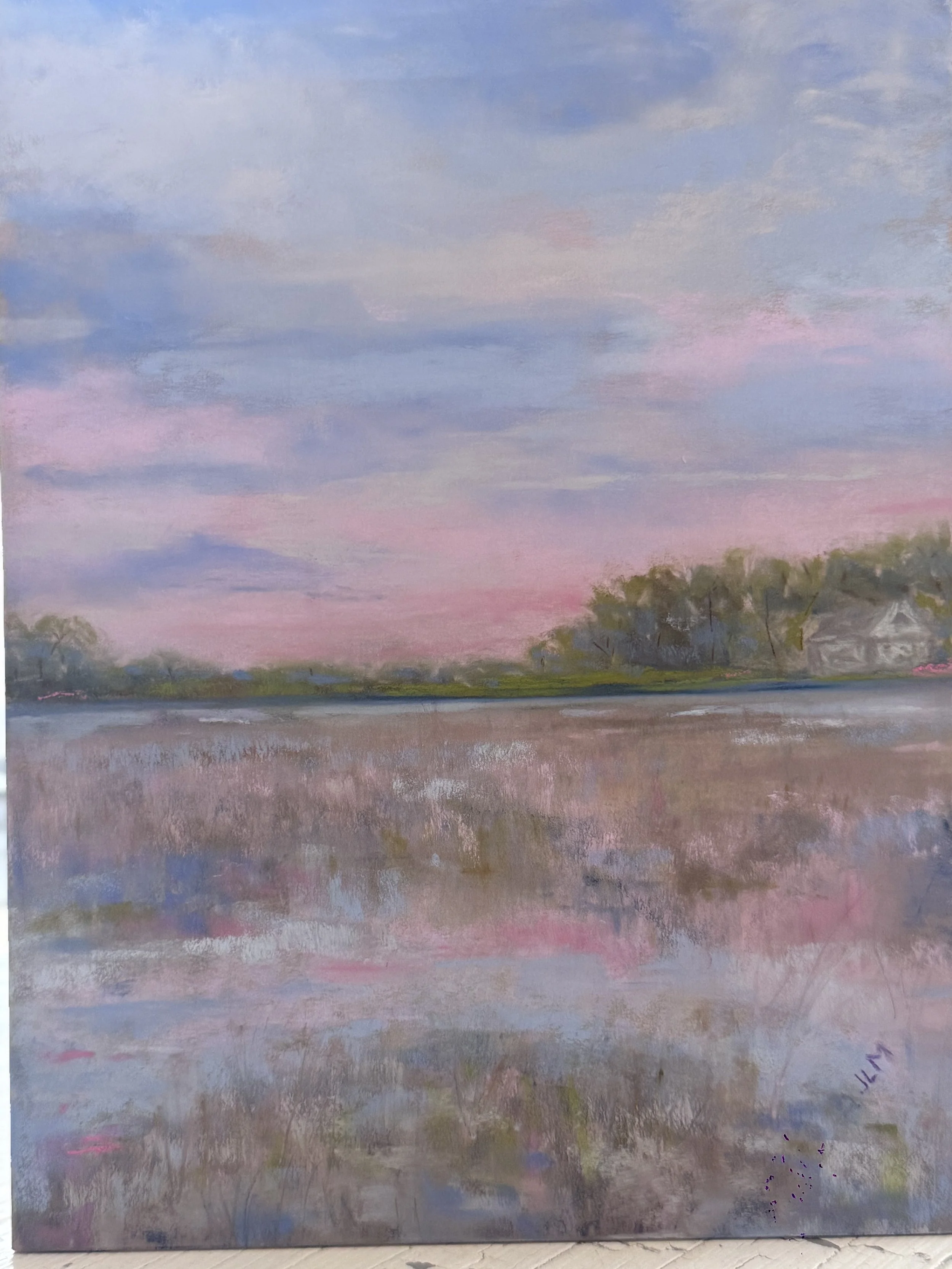 A landscape painting of a peaceful river scene at sunset or sunrise with soft pastel hues of blue, pink, and purple in the sky, and trees and houses in the distance reflected in the water.