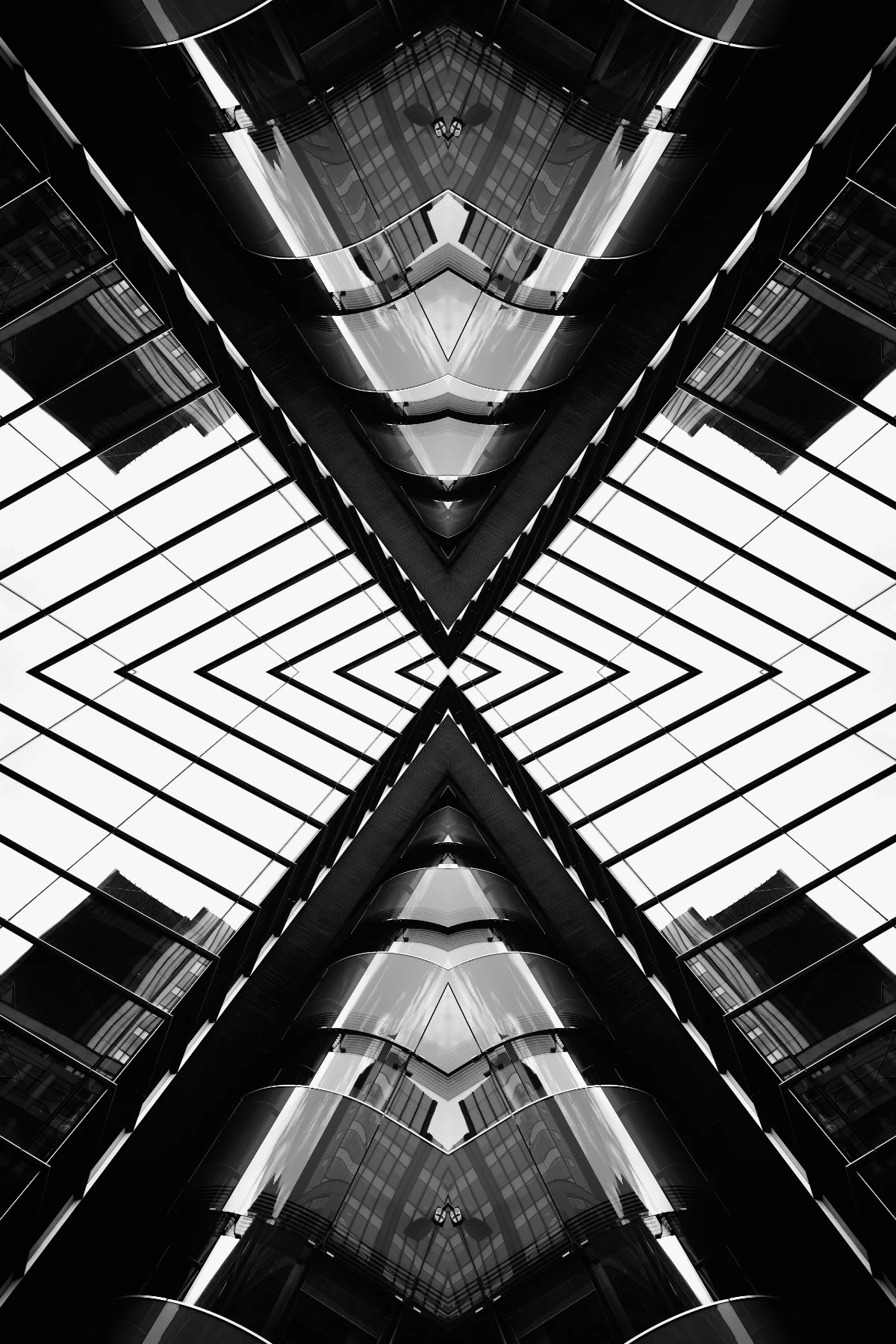 Symmetrical black and white photograph looking up at the glass exterior of a modern multi-story building, creating a mirrored, geometric pattern.