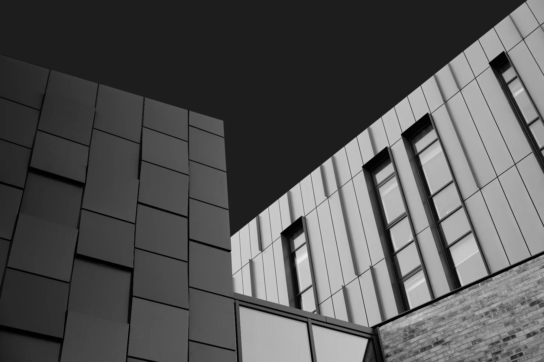 Black and white photo of modern building with geometric windows and panels.