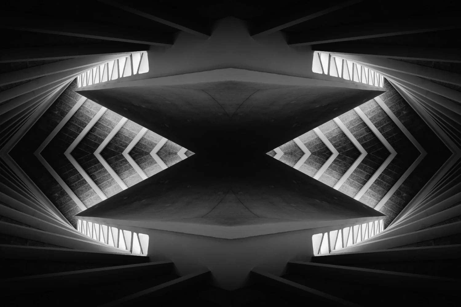 Symmetrical black and white architectural interior shot with shadows and light reflections showing multiple levels and staircases.