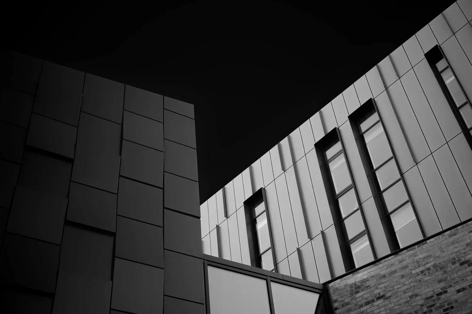 Black and white photo of a modern building with rectangular windows and geometric architectural design.