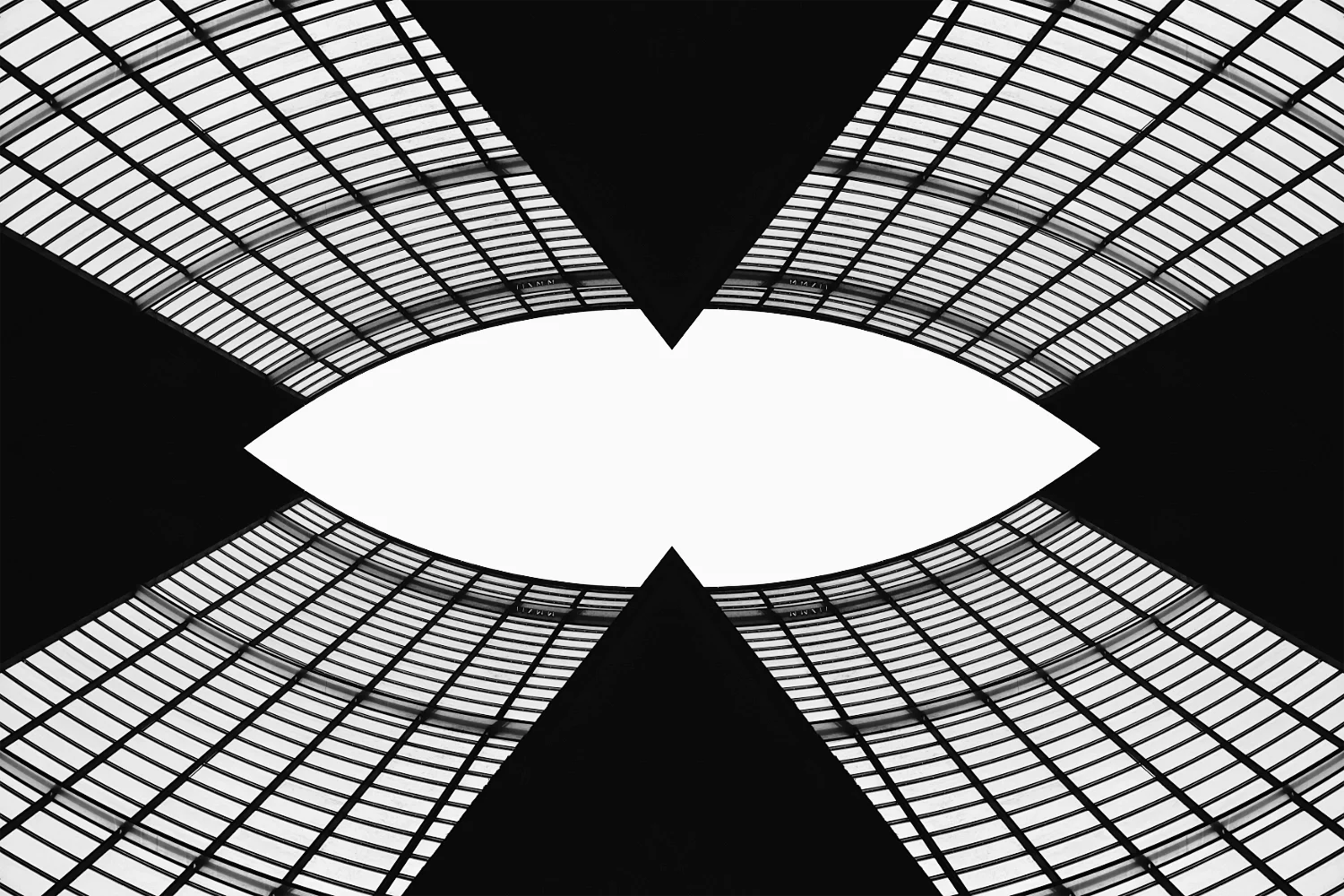 Looking up at a modern glass building with a symmetrical pattern, black and white, creating an abstract geometric design.