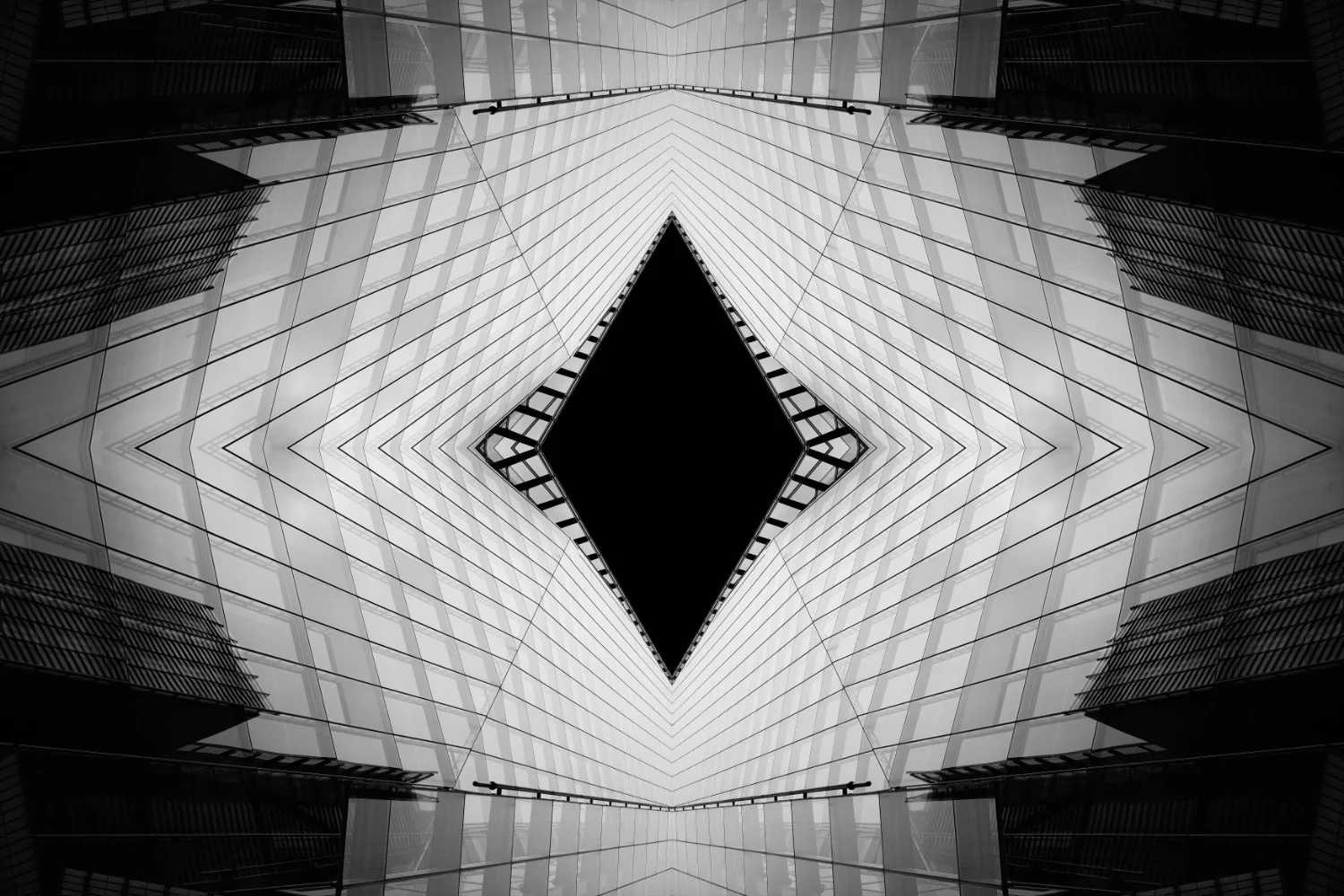 Black and white abstract image of a modern glass building with symmetrical pattern and geometric shapes, creating a sense of depth and perspective.