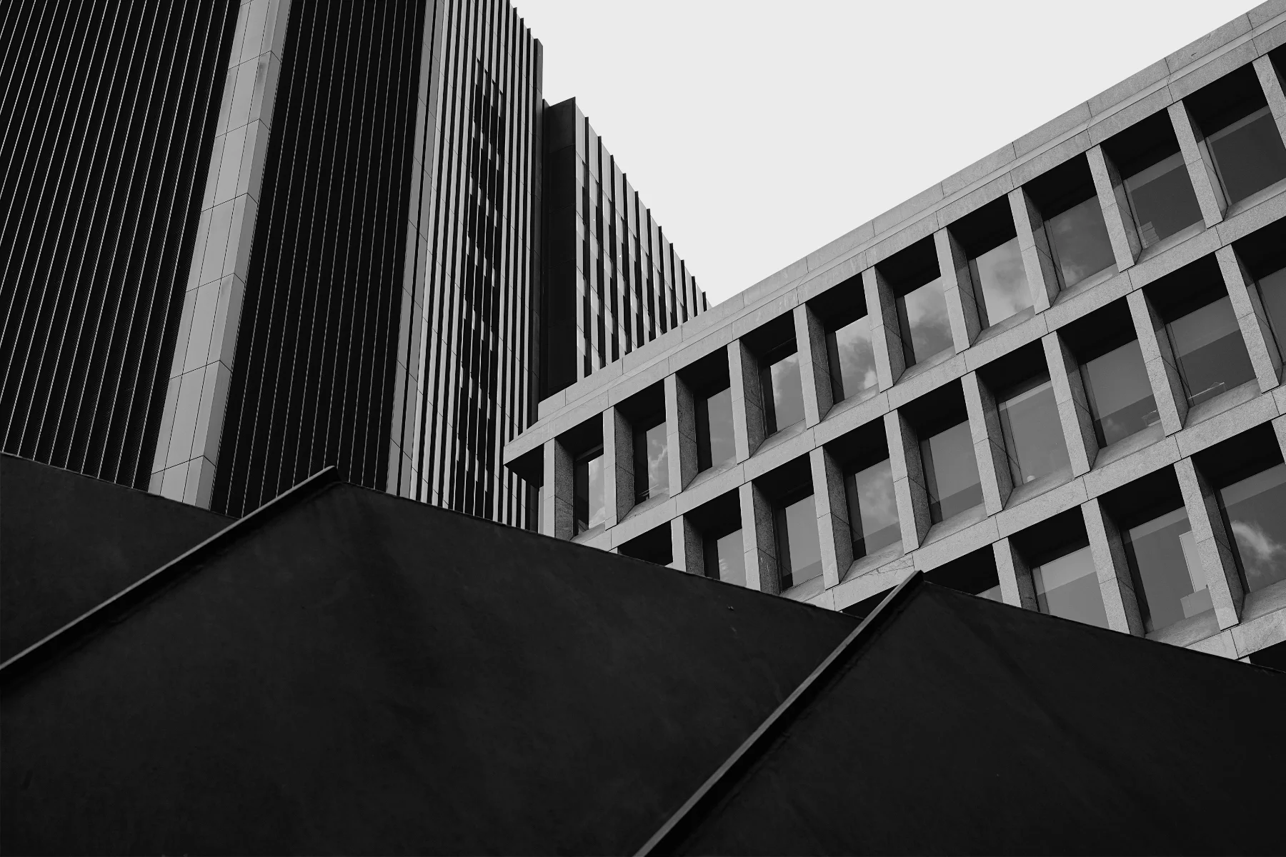 Black and white photo of modern skyscrapers viewed from below, showcasing geometric patterns and glass windows.