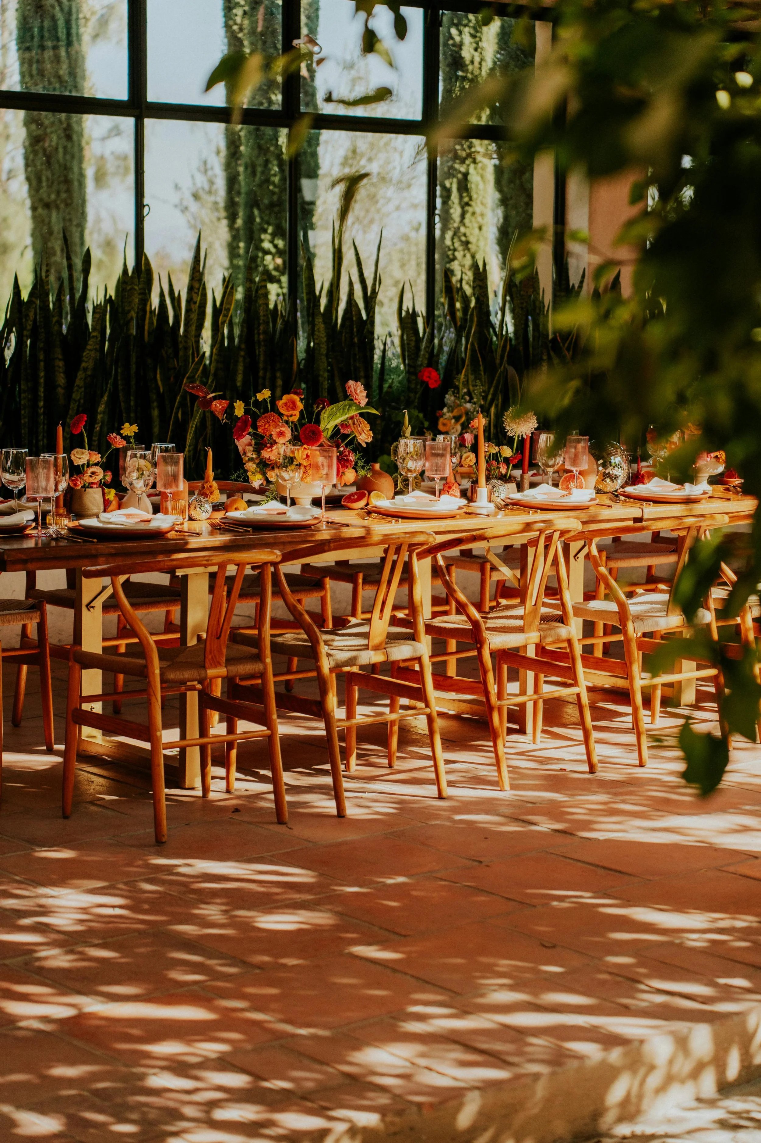 Table de mariage dressée sous une verrière avec compositions florales colorées