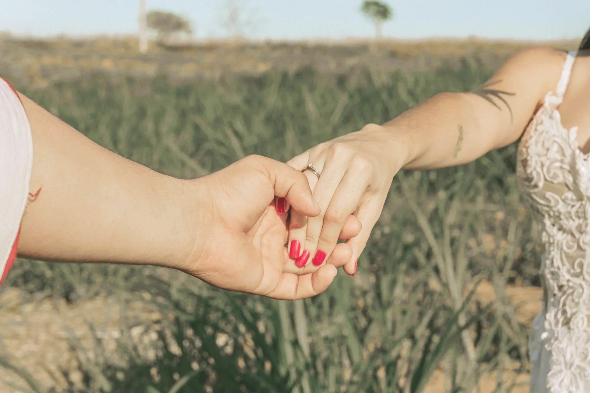 Mains d'un couple avec bague de fiançailles dans un champ