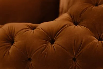 Close-up of a brown tufted upholstered furniture piece, likely a sofa or chair.