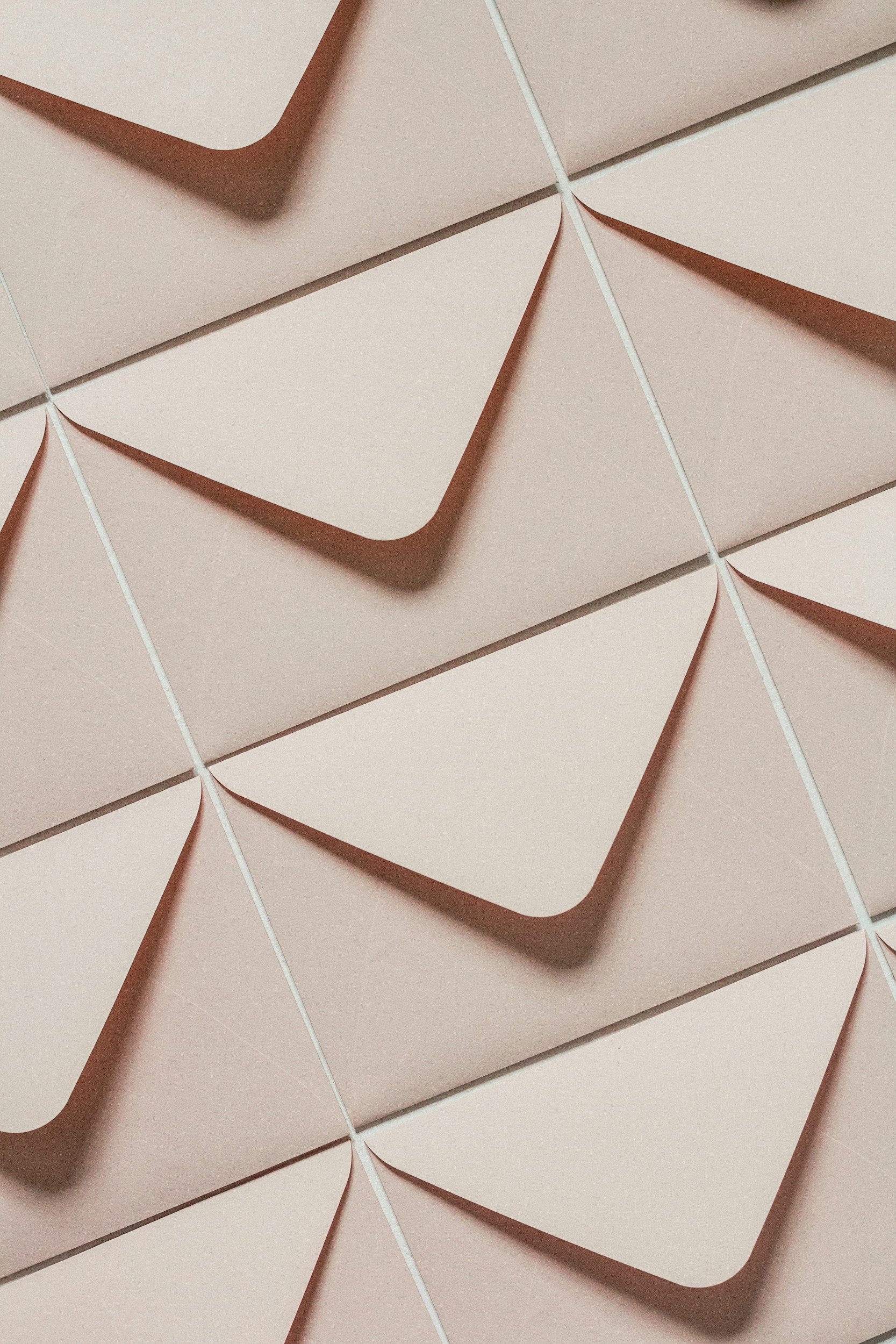 Close-up of pink envelopes arranged in a grid pattern with triangular flaps and white string closures.