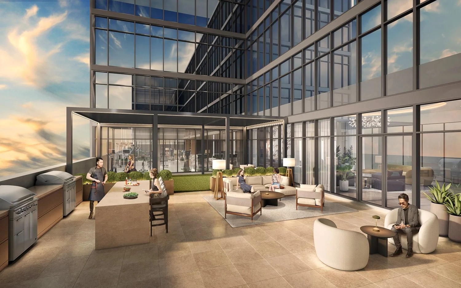 Modern outdoor rooftop lounge with seating area featuring sofas, chairs, and large potted plants, adjacent to a glass-walled gym or fitness center, with a city skyline and sunset sky in the background.