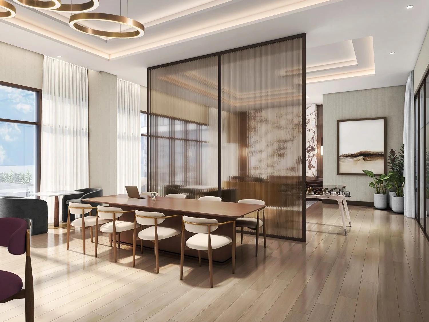 Modern interior of a home or office with a conference table, white chairs, a foosball table, artwork, and decorative plants.