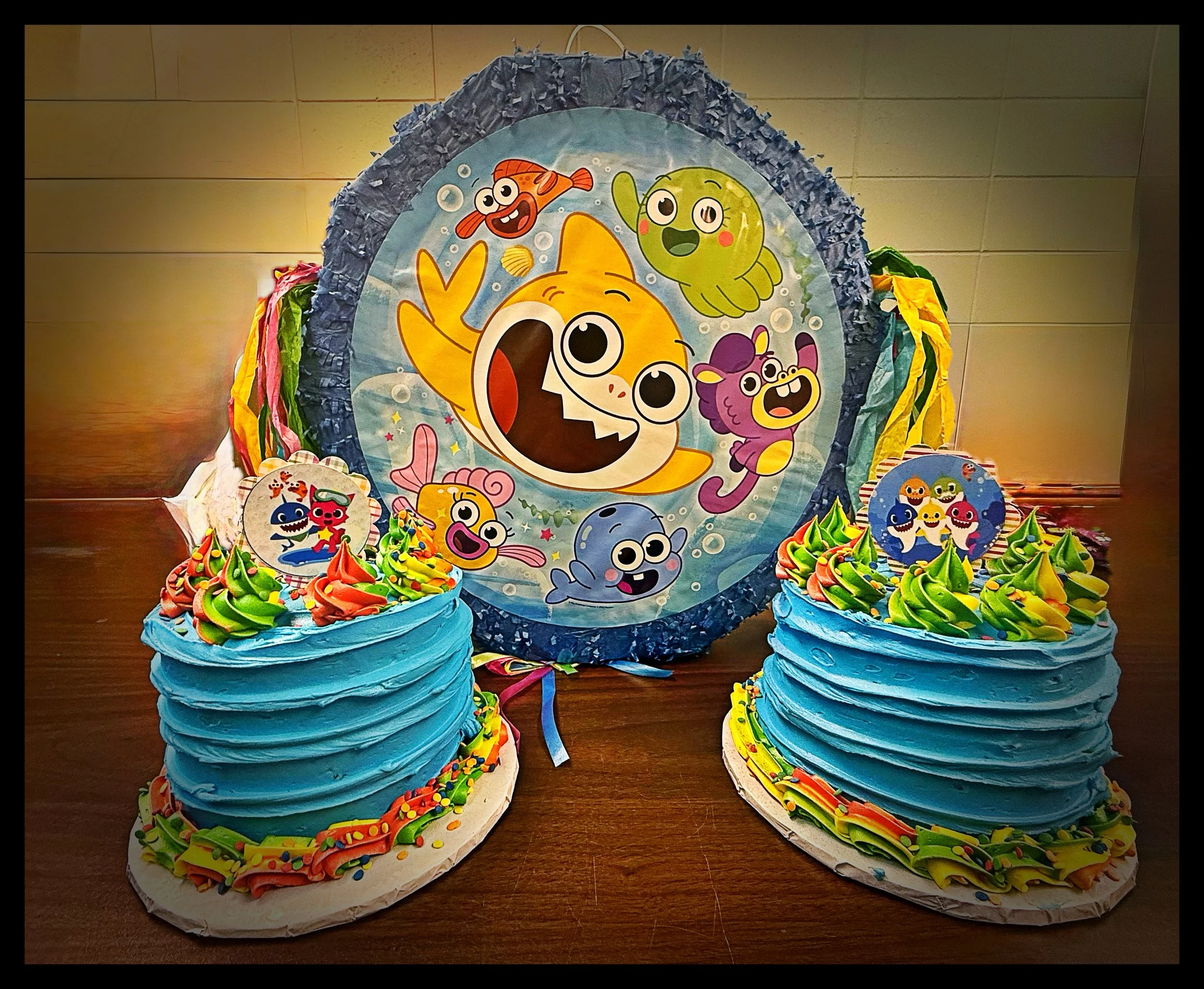 Colorful children's birthday cake and party decorations themed with animated fish characters from Bubble Guppies.