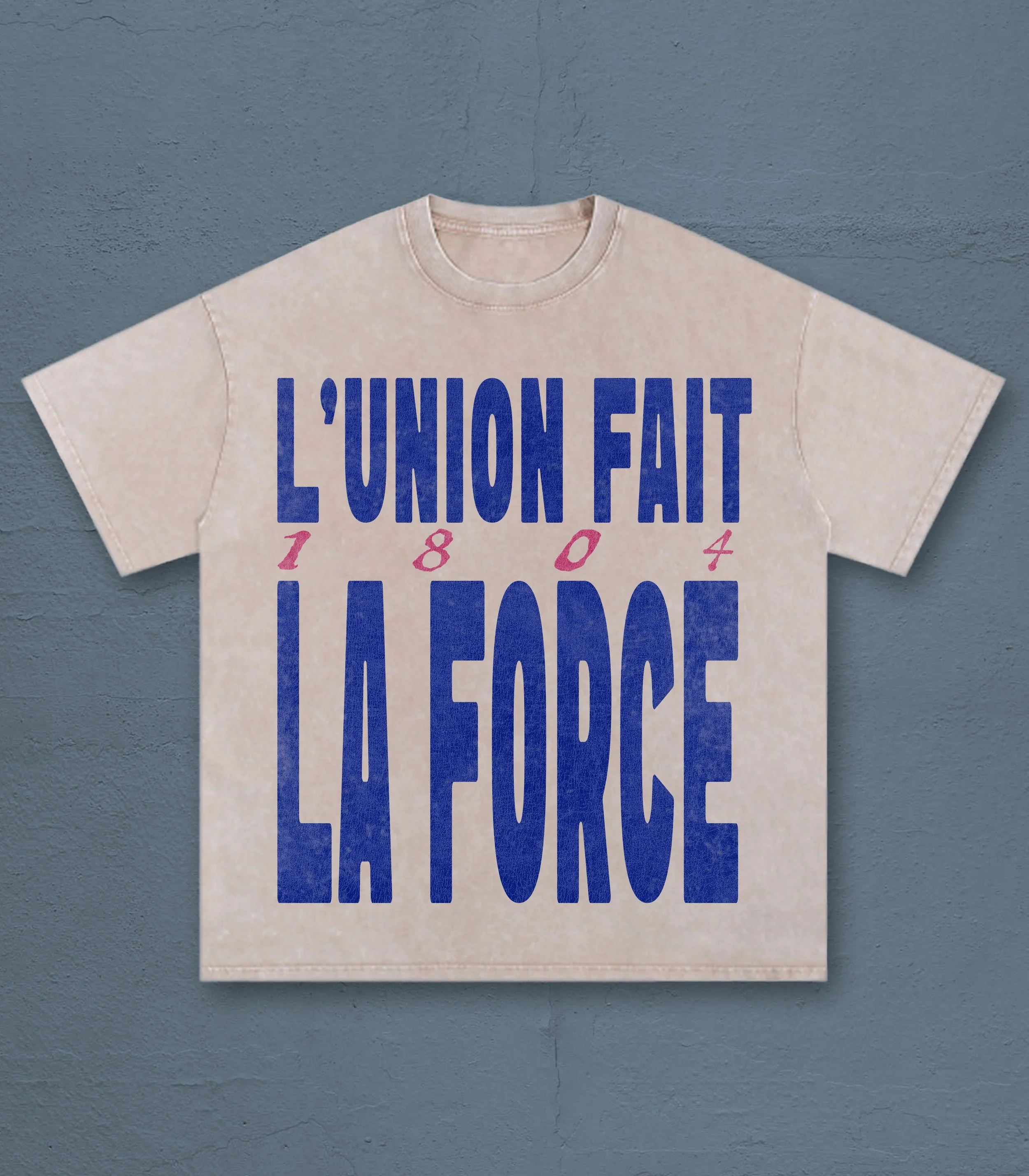 Beige T-shirt with bold blue text reading 'L'UNION FAIT LA FORCE', displayed against a blue textured wall.