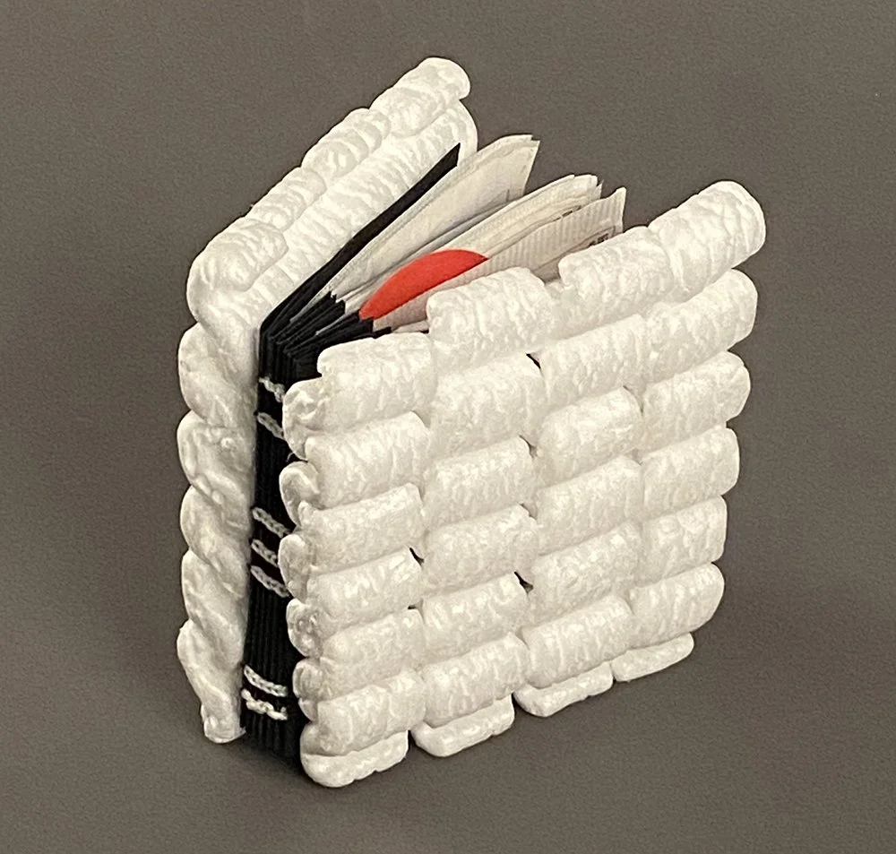 A book made from white packing peanuts, its pages made from packaging materials inside.