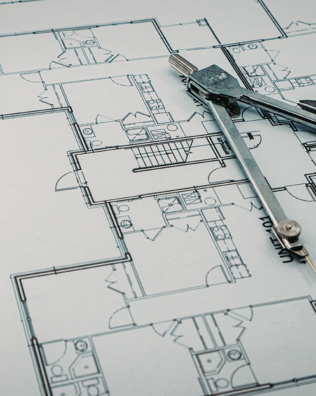 Architectural blueprints of a building with a compass inches on top.