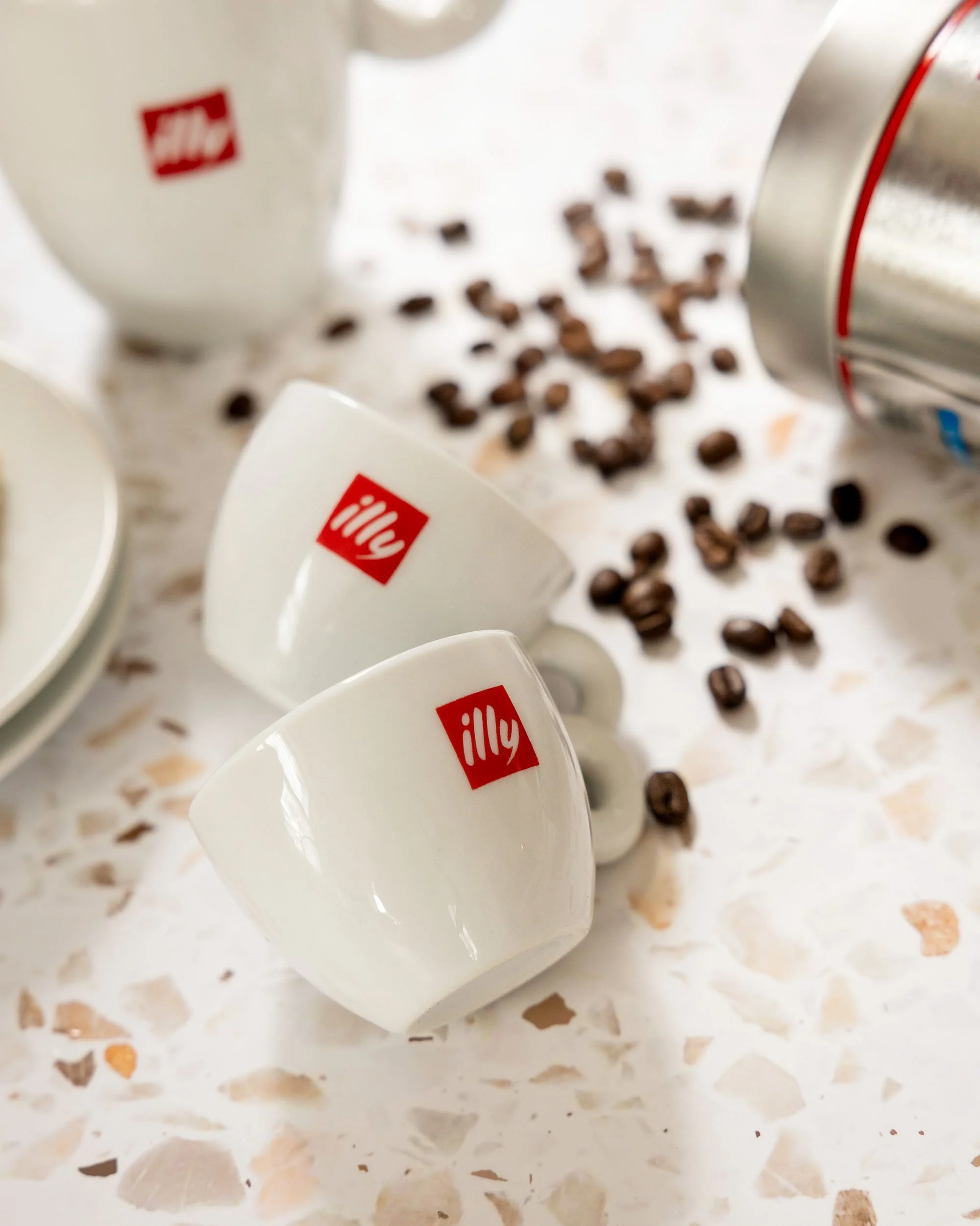 Product photography of Illy coffee cups with beans styled on terrazzo surface in natural light