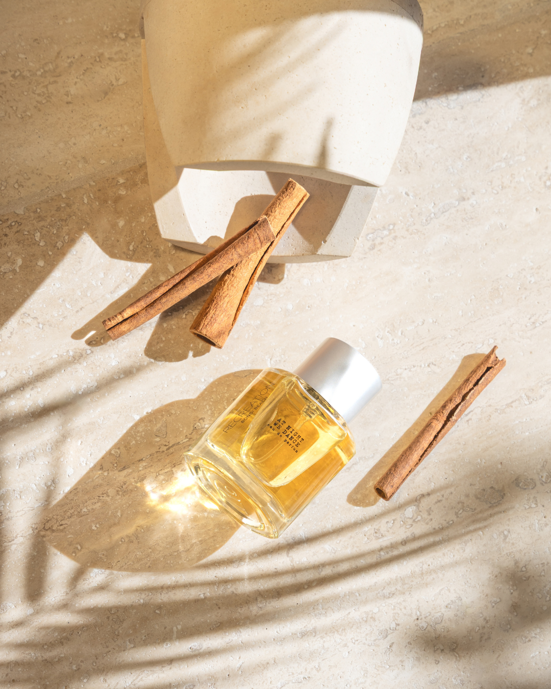 Sydney product photographer perfume bottle styled in natural light with warm tones and shadow detail