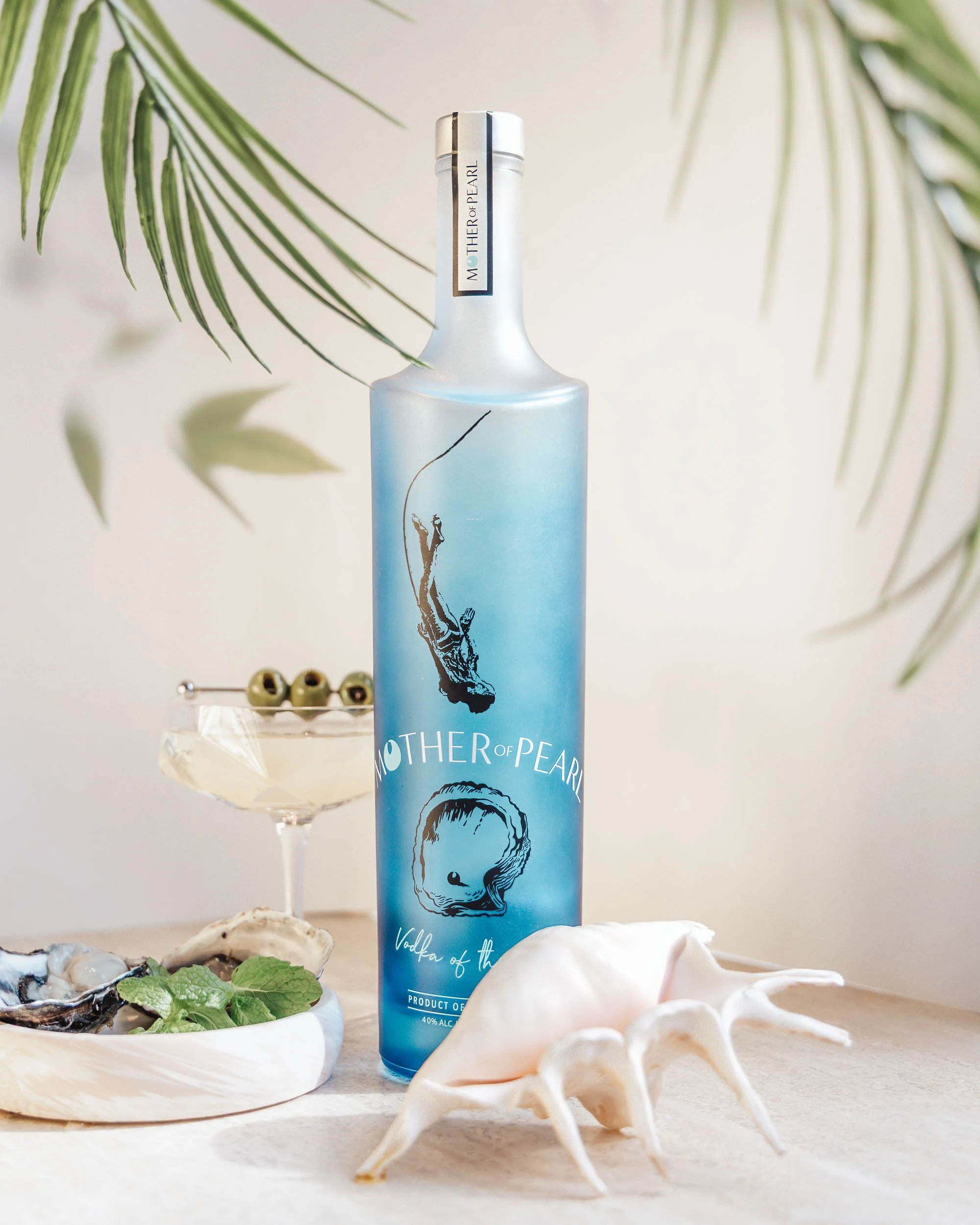 Premium vodka bottle styled with oyster, cocktail and soft natural light