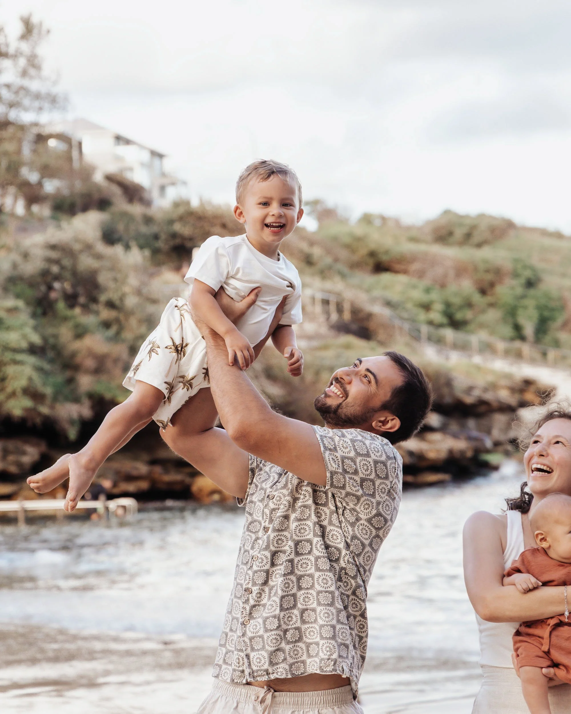 Father lifting child at the beach in a joyful moment captured by Georgie Meadows Creative Sydney  