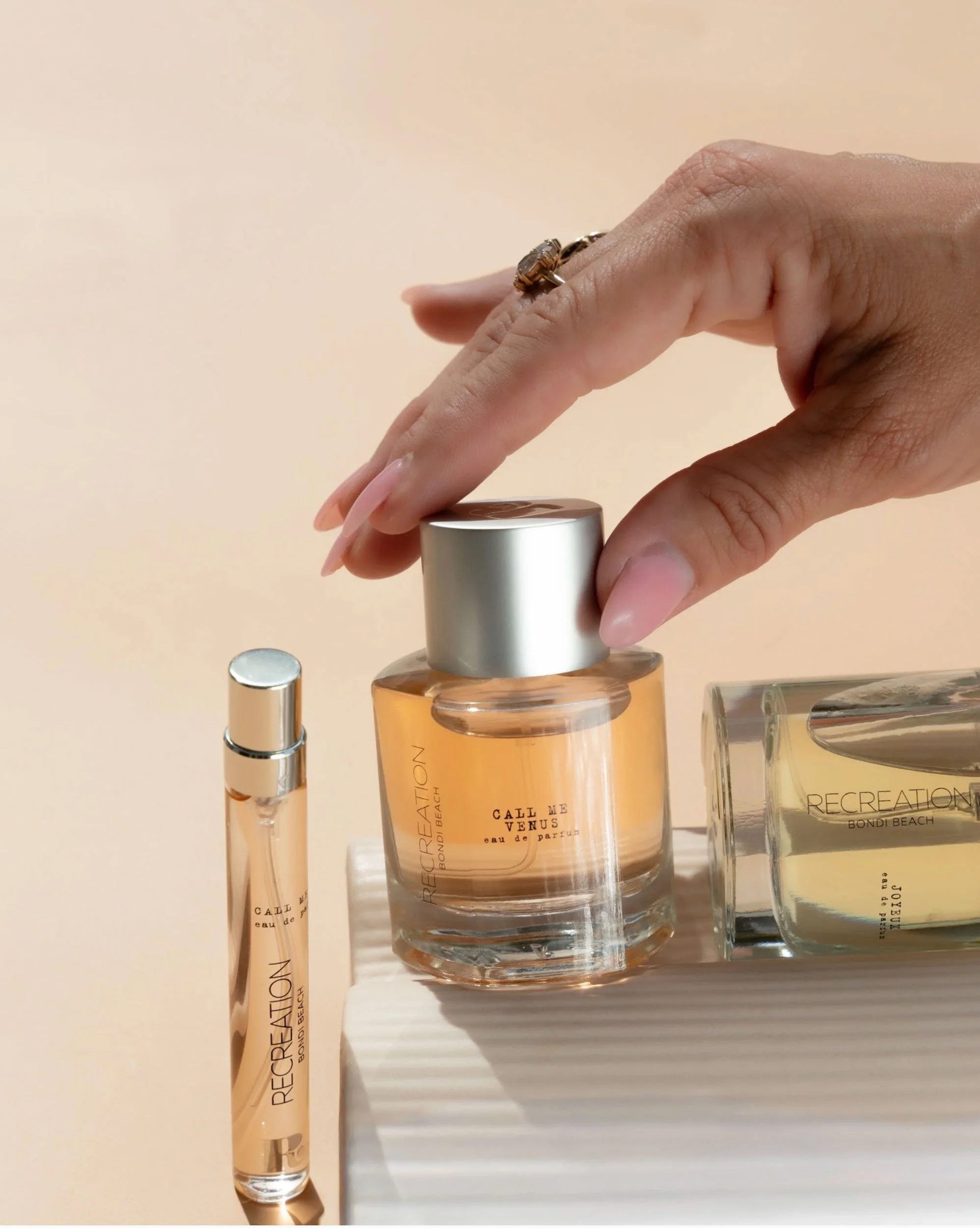 Product photography of perfume bottles with hand detail in warm natural light