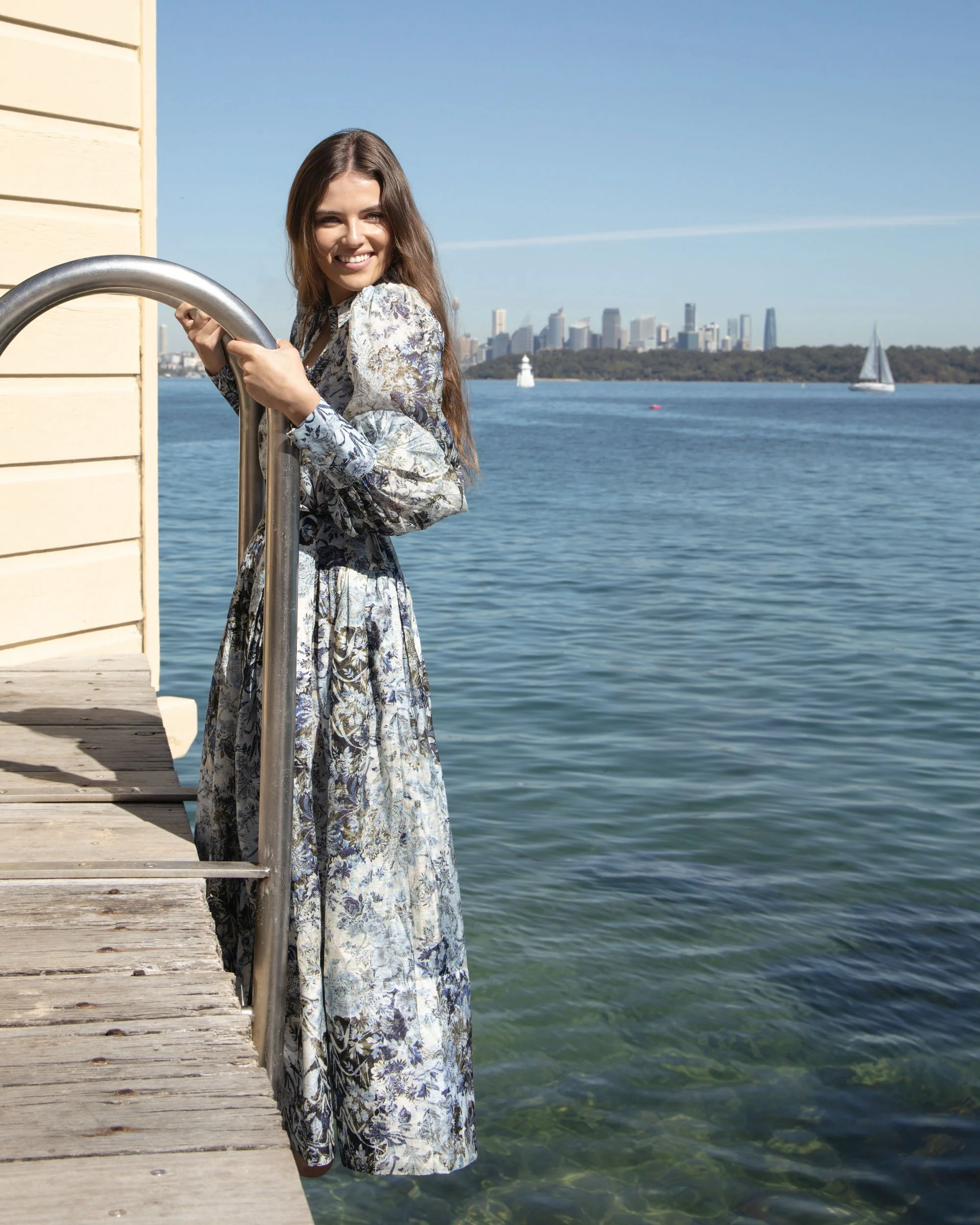 Lifestyle fashion photography of woman on jetty with Sydney harbour and city skyline in background