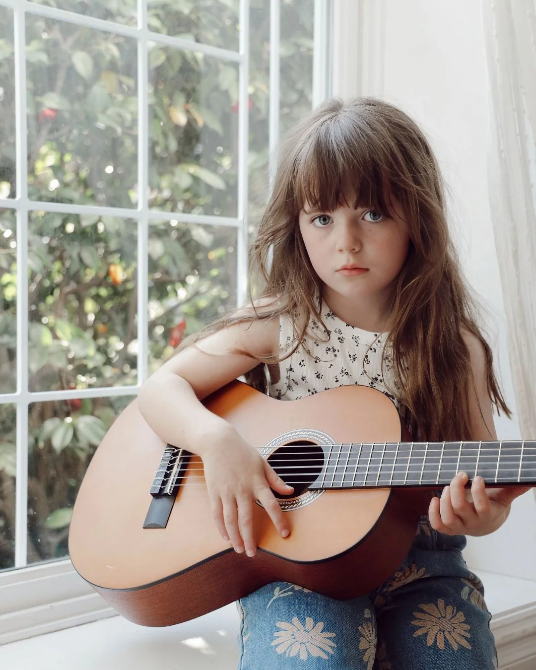 Sydney family photographer natural light portrait of child playing guitar by window