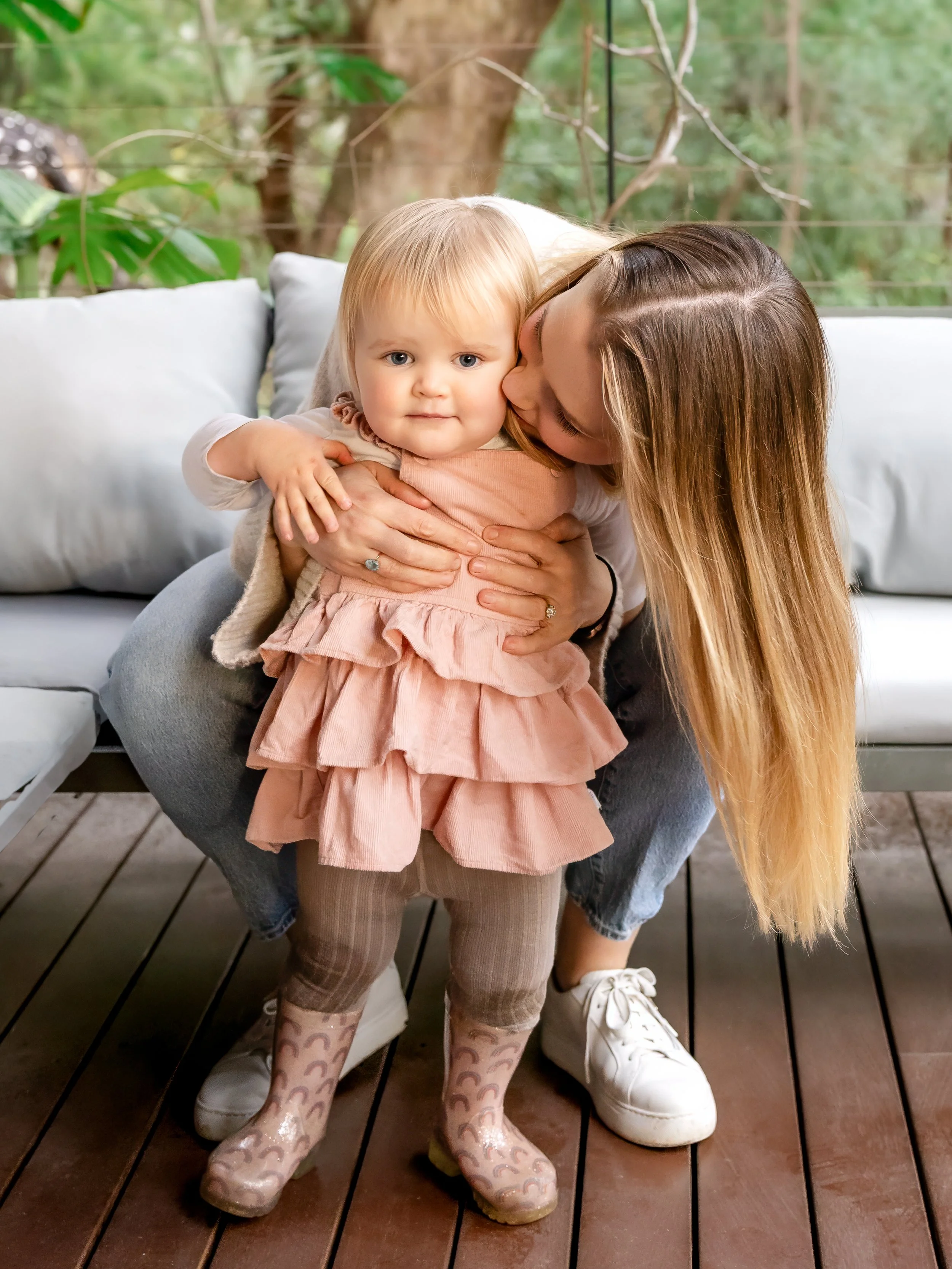 Mother kissing toddler daughter during rainy family photography session in Sydney