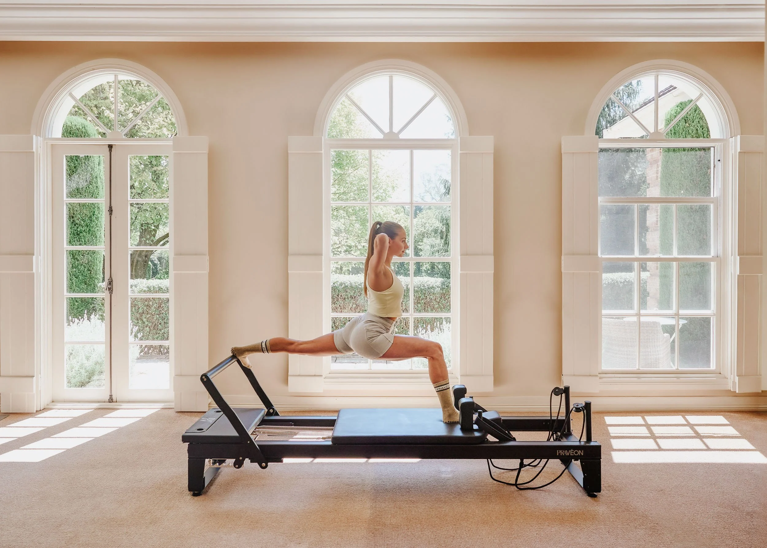 Wide shot of pilates reformer in light-filled studio with arched windows and natural light