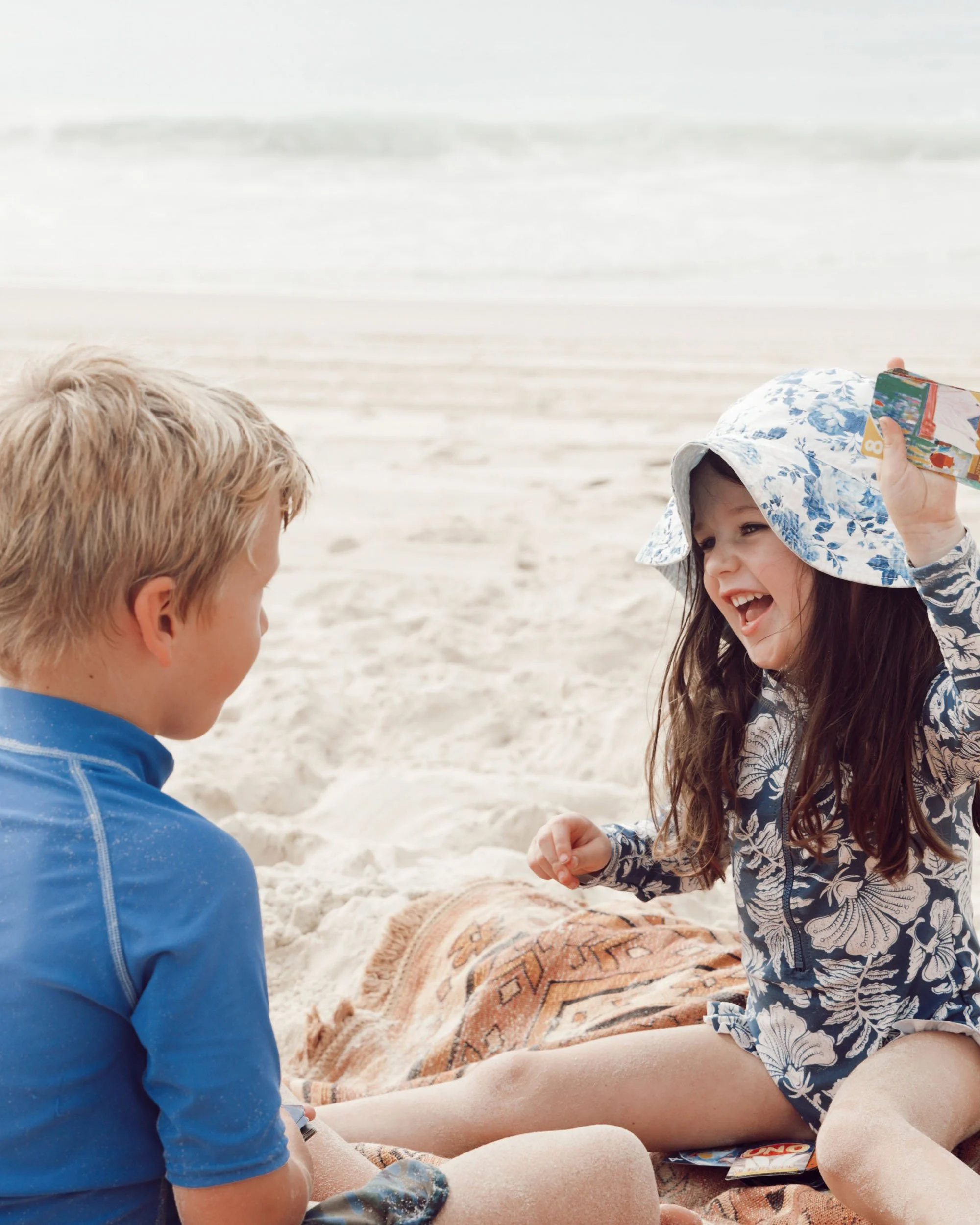 Children sitting together on the beach in a candid moment by Georgie Meadows Creative Sydney  